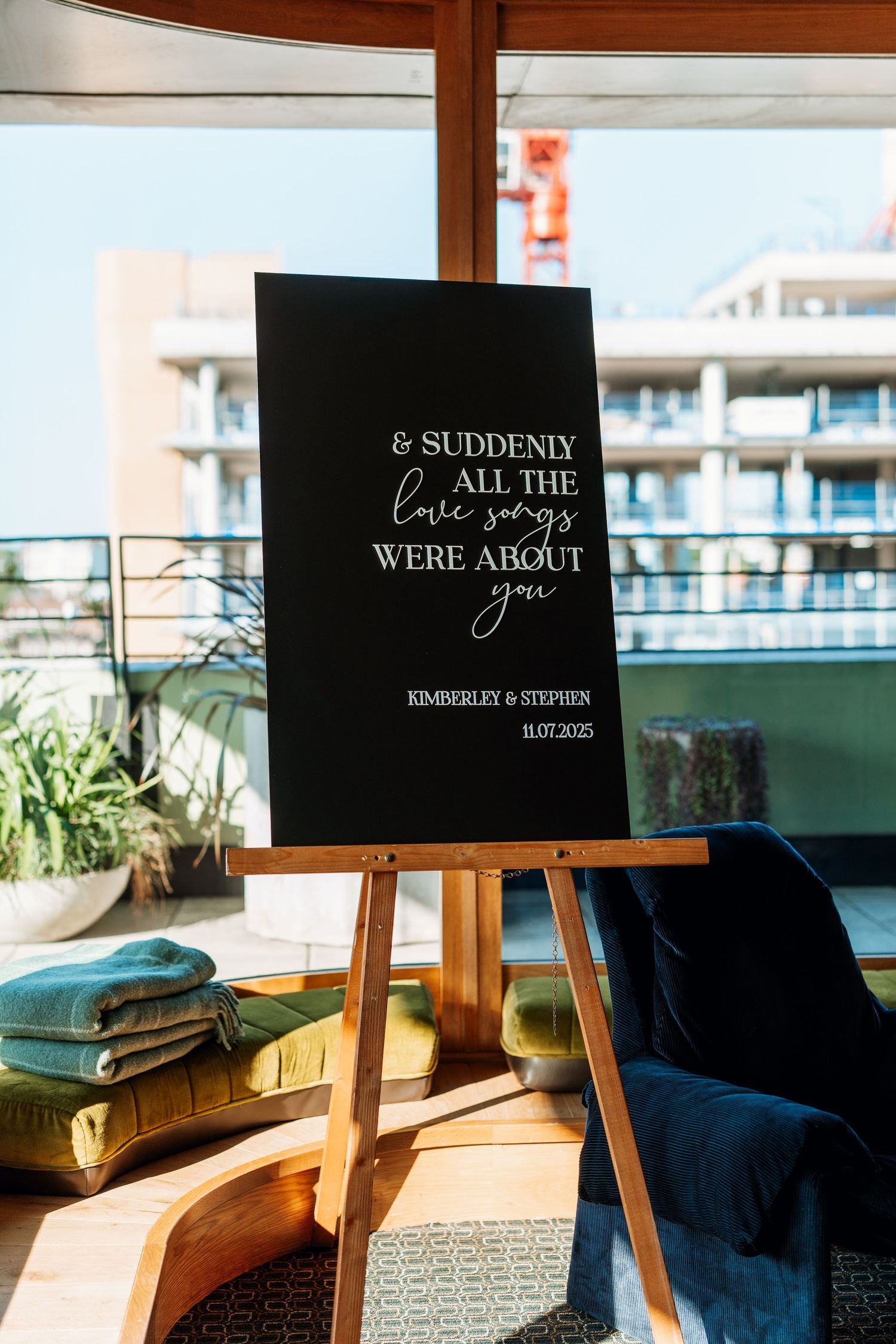Wedding signage displayed on wooden easels in a sunlit room with modern decor.