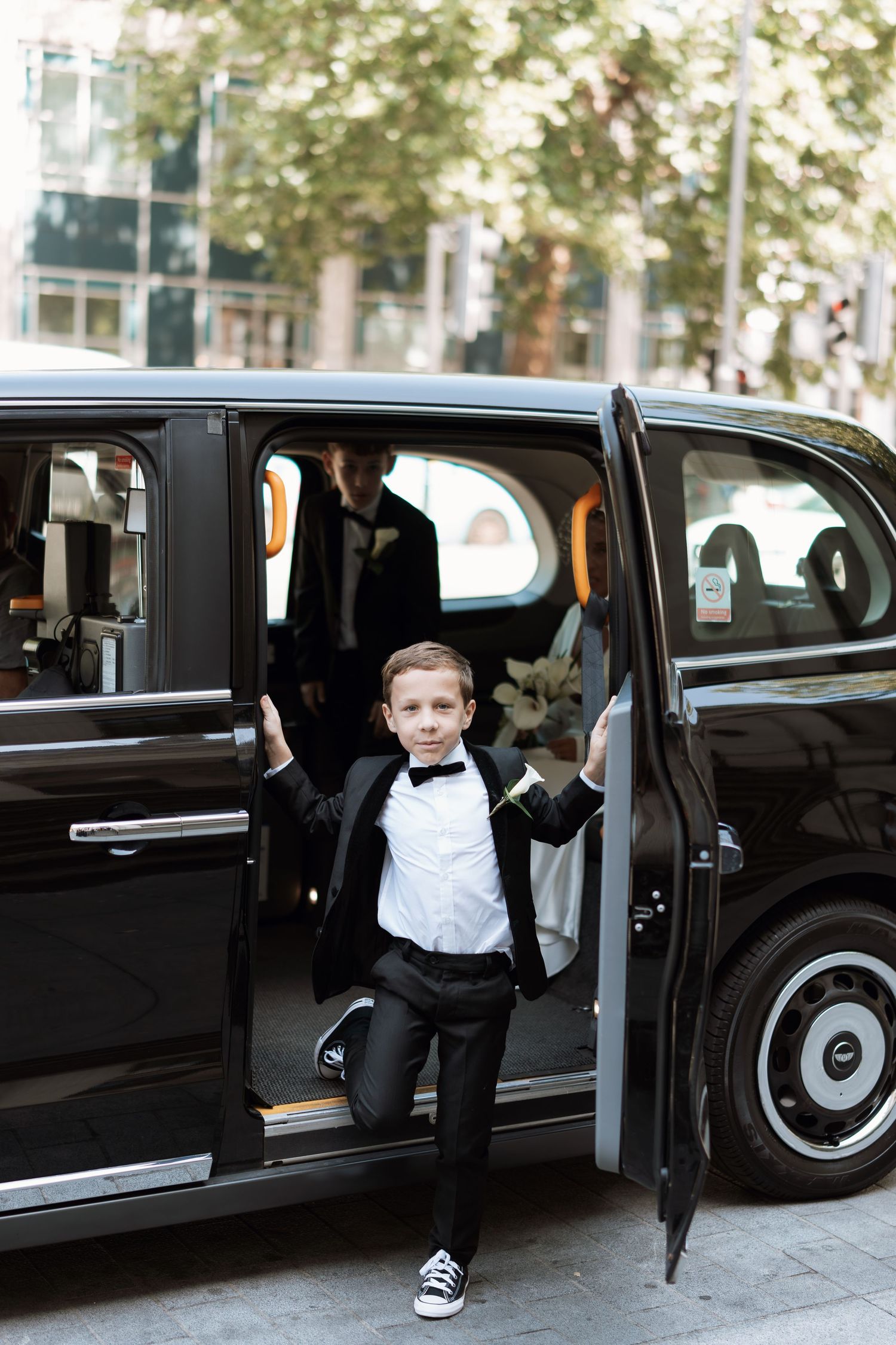 Wedding party members exit a sleek black limousine in formal attire.