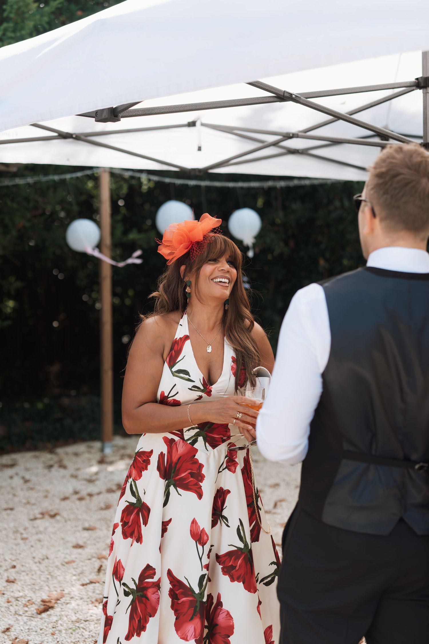 Wedding guests in formal attire dancing under white canopy tents at an outdoor celebration.