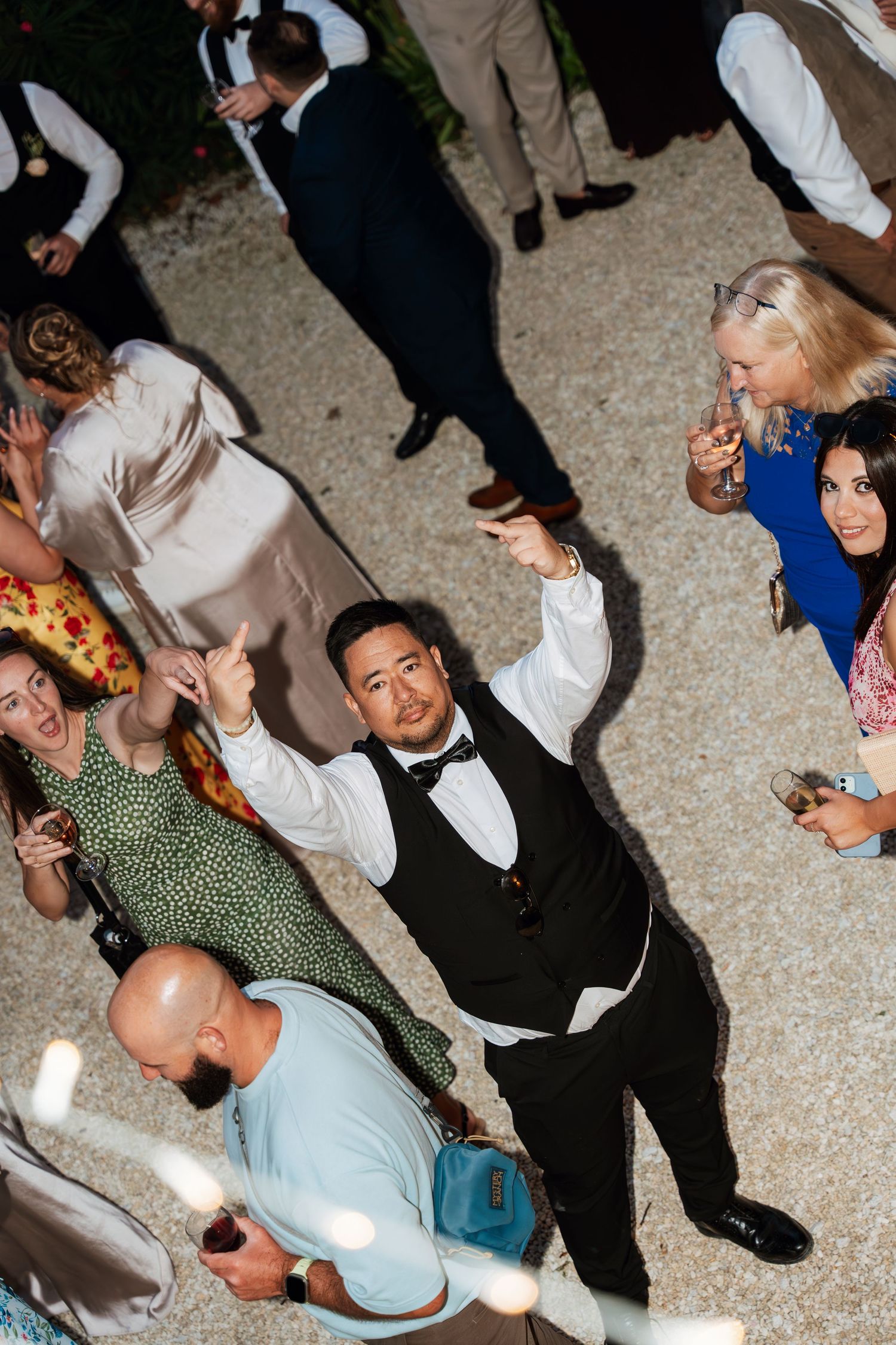 Wedding reception dance floor filled with joyful guests dancing under string lights.