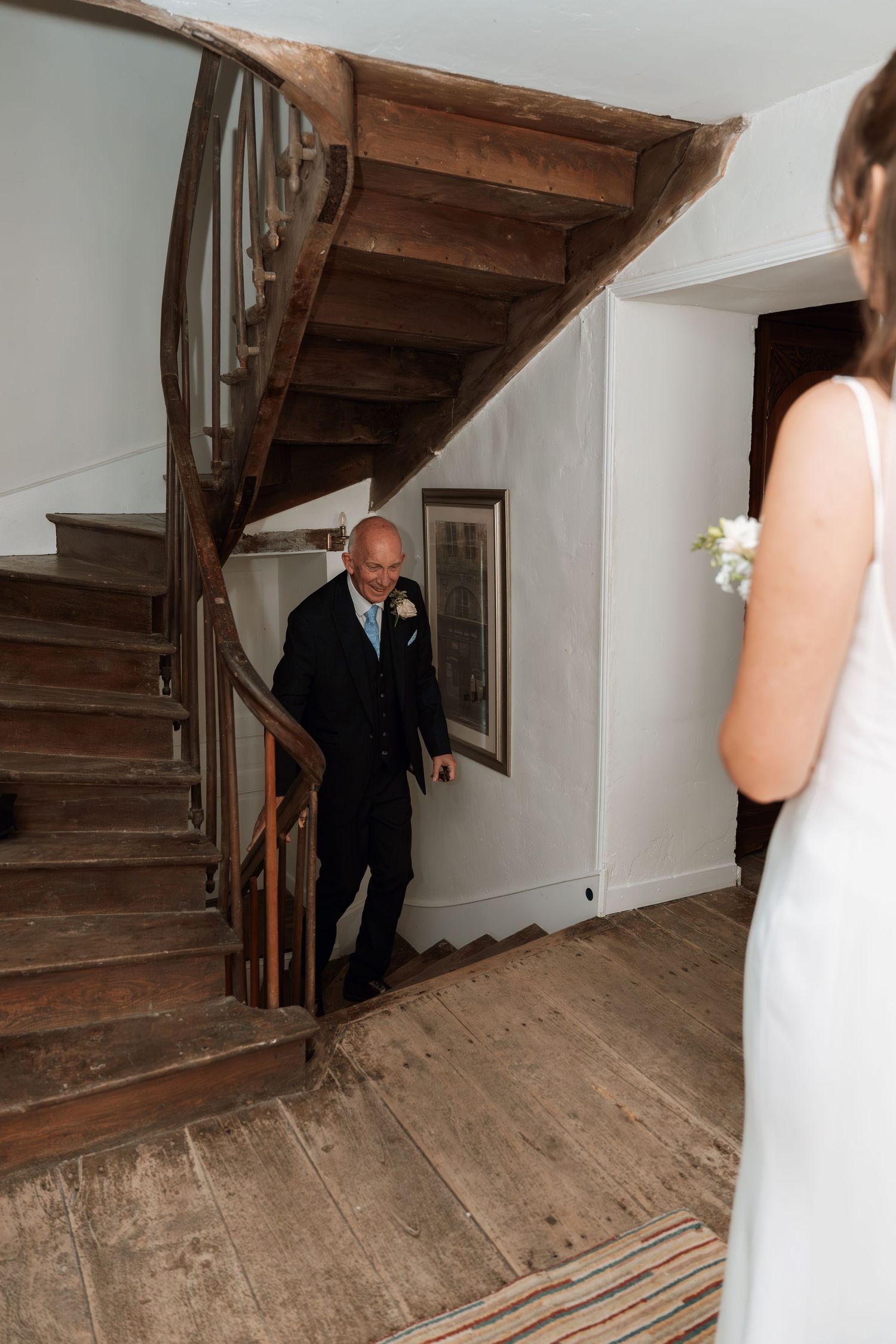 Sequence showing someone descending wooden stairs in formal attire.