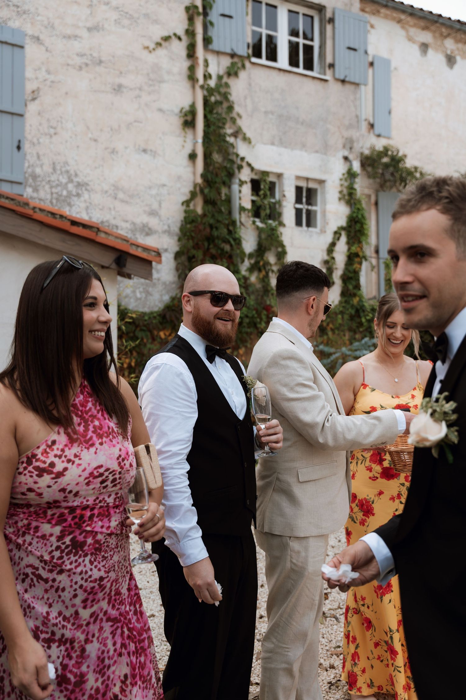 Wedding guests in colorful dresses and formal attire mingle during an outdoor reception.