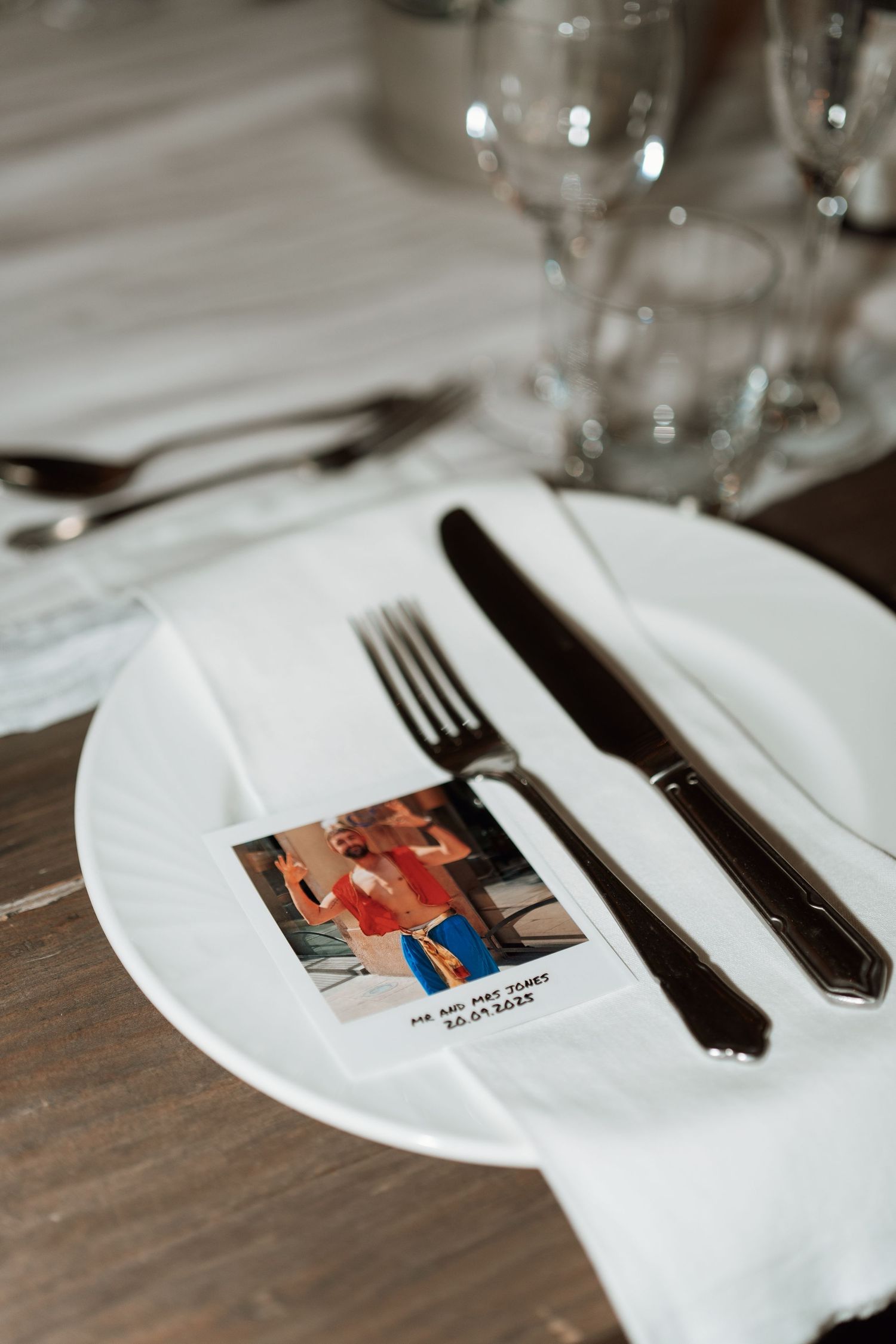 Place setting at a wedding reception with vintage photos and elegant silverware.