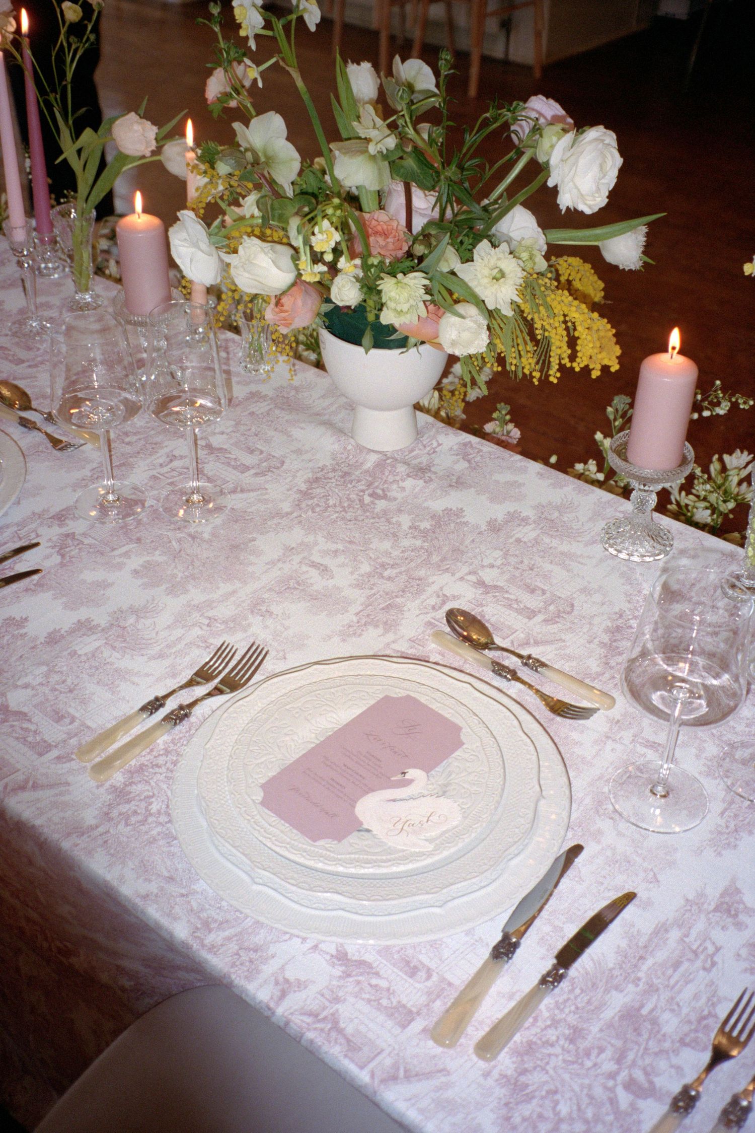 Elegant table settings with pink and white damask linens, crystal stemware, and delicate floral centerpieces create a romantic ambiance.