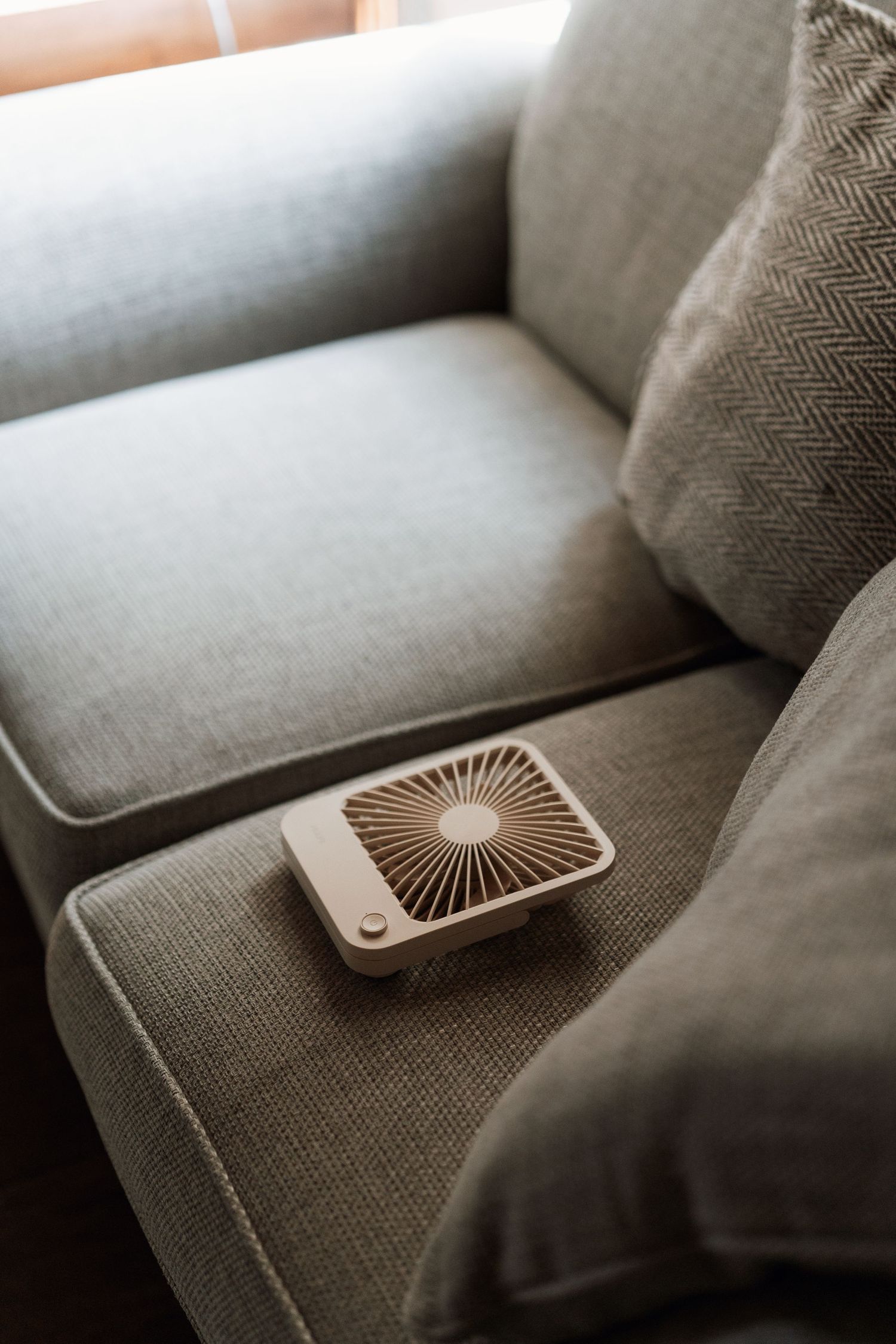 A decorative fan resting on gray couch cushions showing a sequence of placement positions.