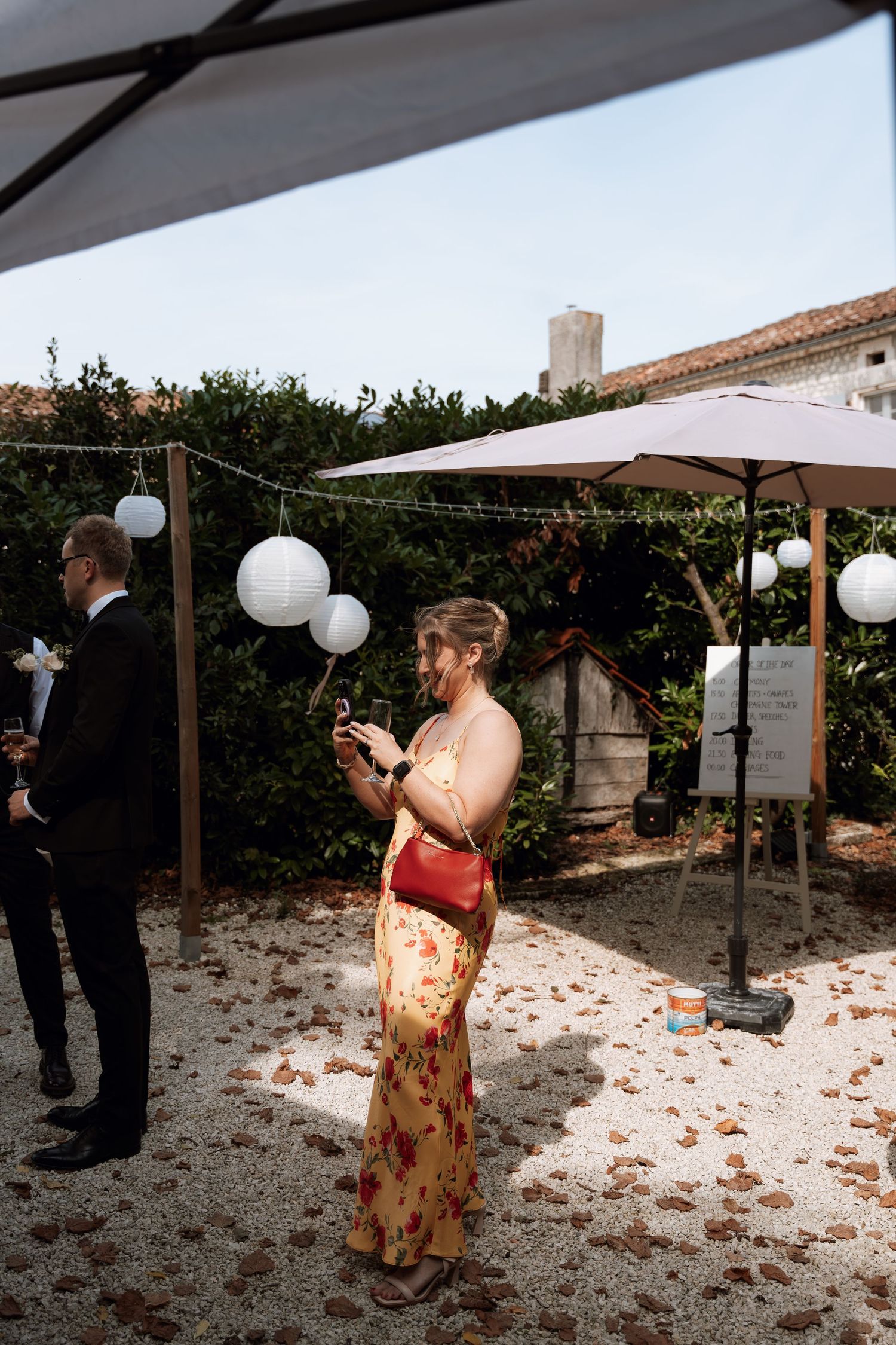 Photographer captures candid moments under white lanterns at an outdoor event.