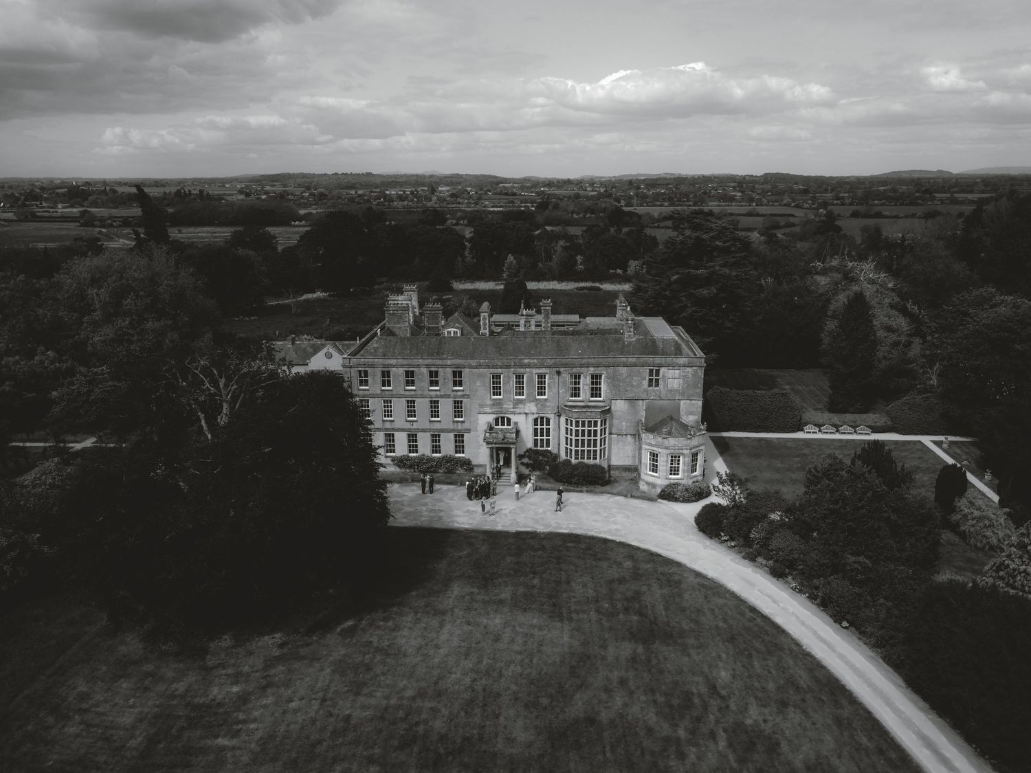 Aerial black and white panoramic view of a grand estate with manicured grounds.