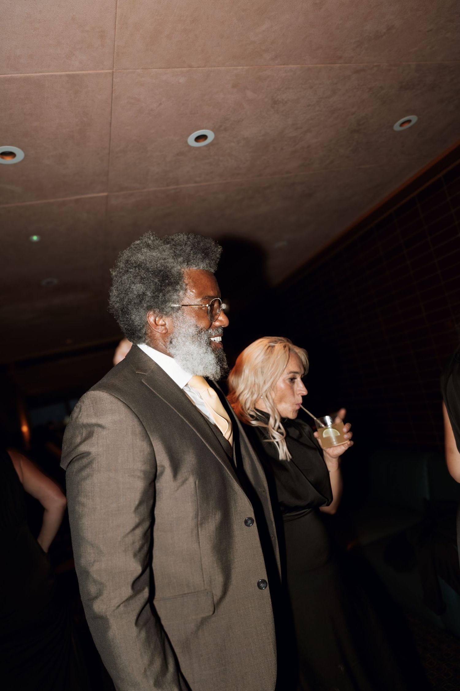 People in formal attire dancing at a dimly lit wedding reception.