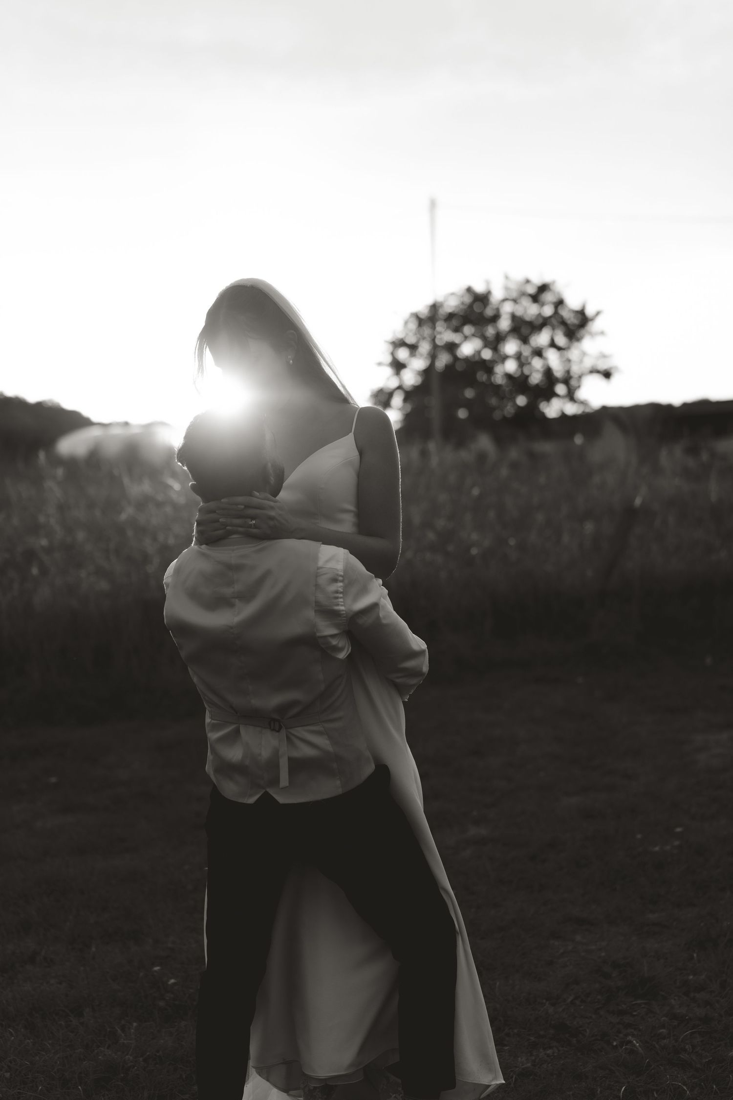 Couple embracing in silhouette against sunset in black and white photography.