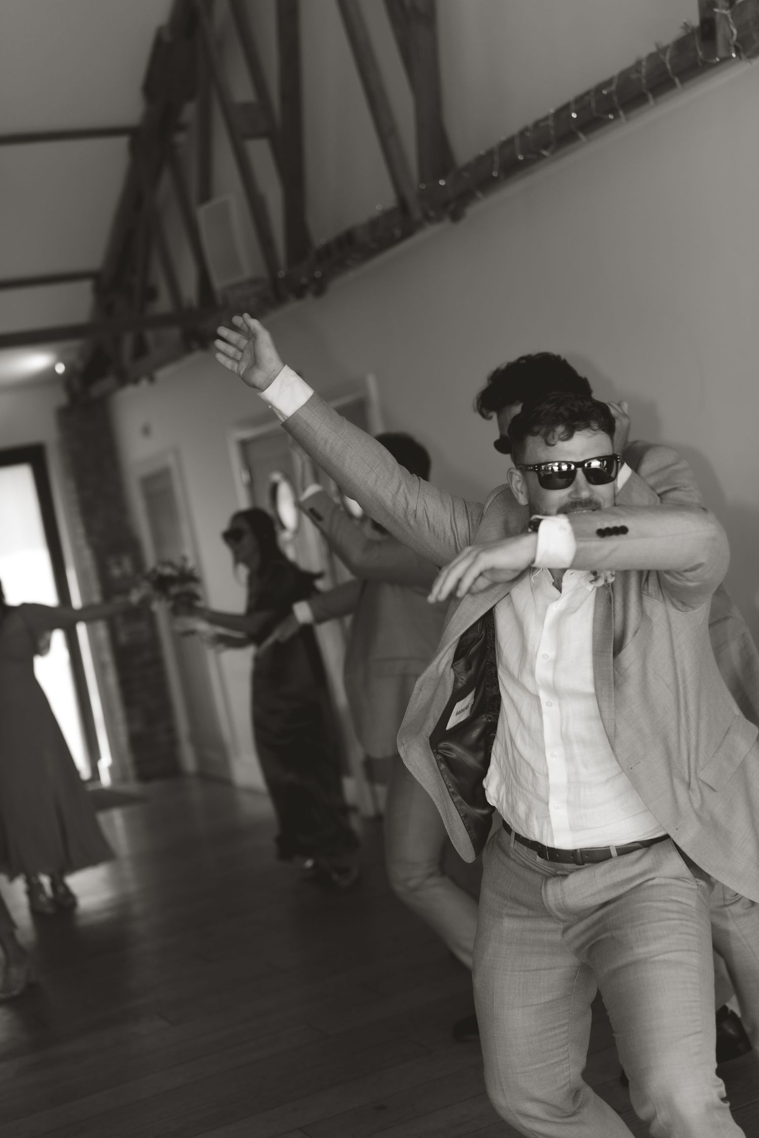 Black and white photo of wedding guests dancing enthusiastically at a reception.