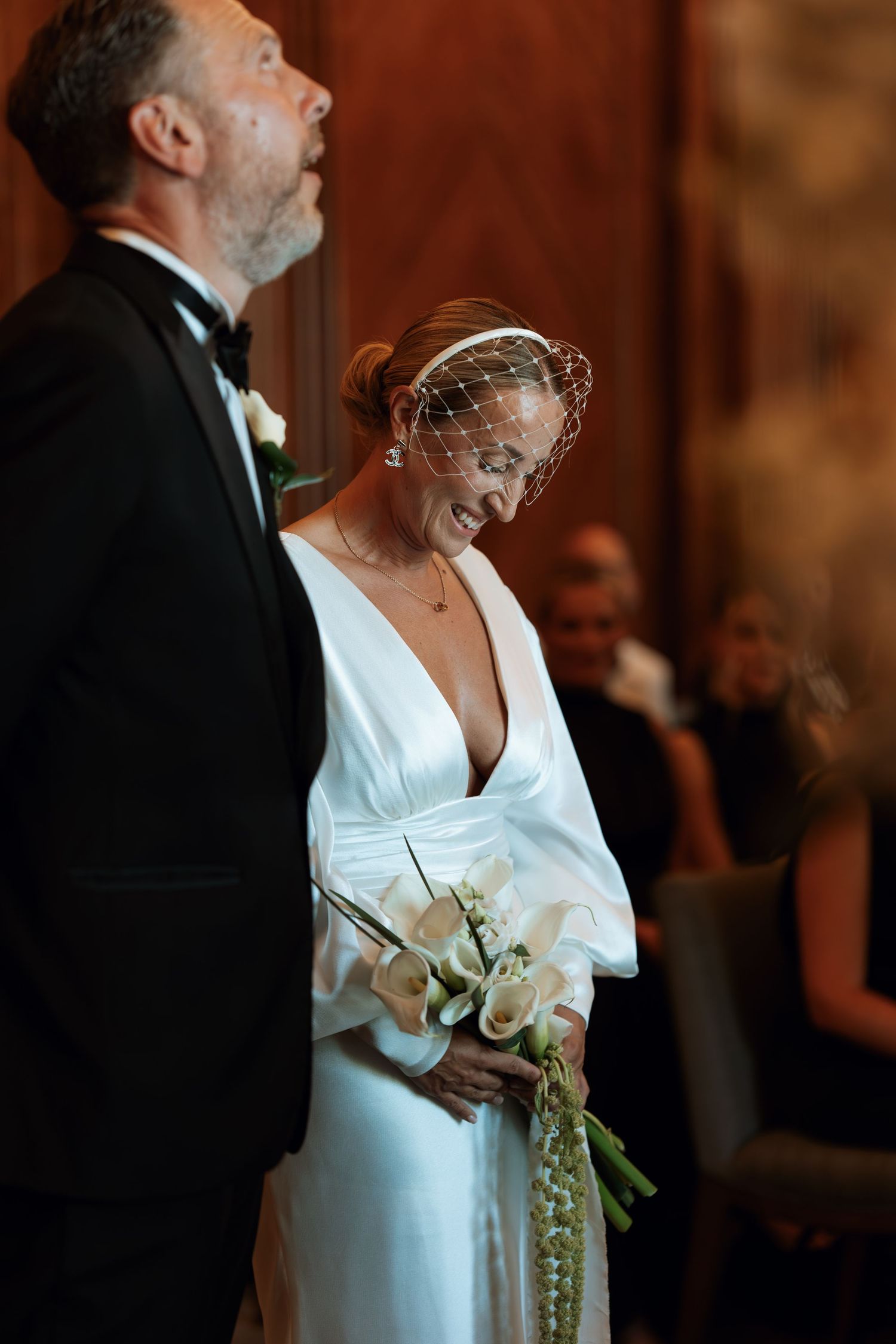 Elegant bride in white dress holding a bouquet during a formal wedding ceremony.