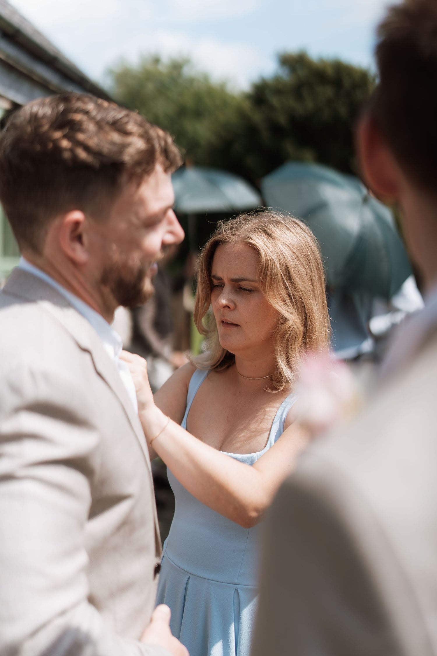 Couple in formal attire sharing an intimate moment outdoors on a sunny day.