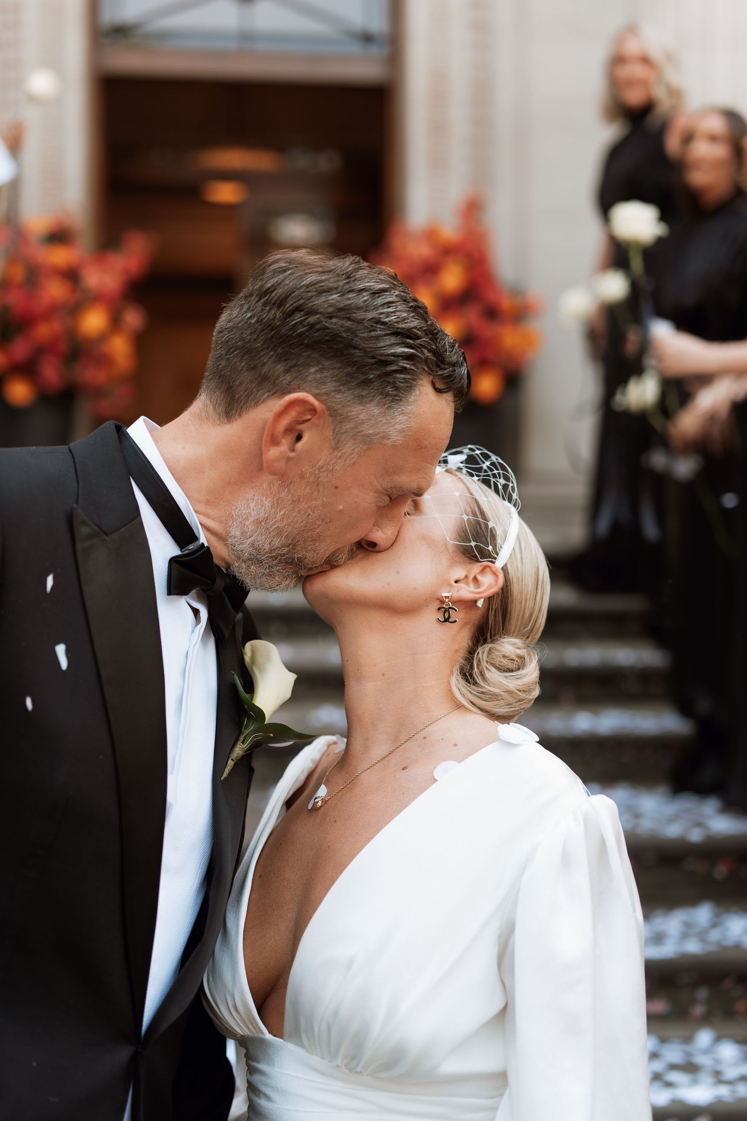 Romantic wedding kiss on steps with confetti falling around couple.