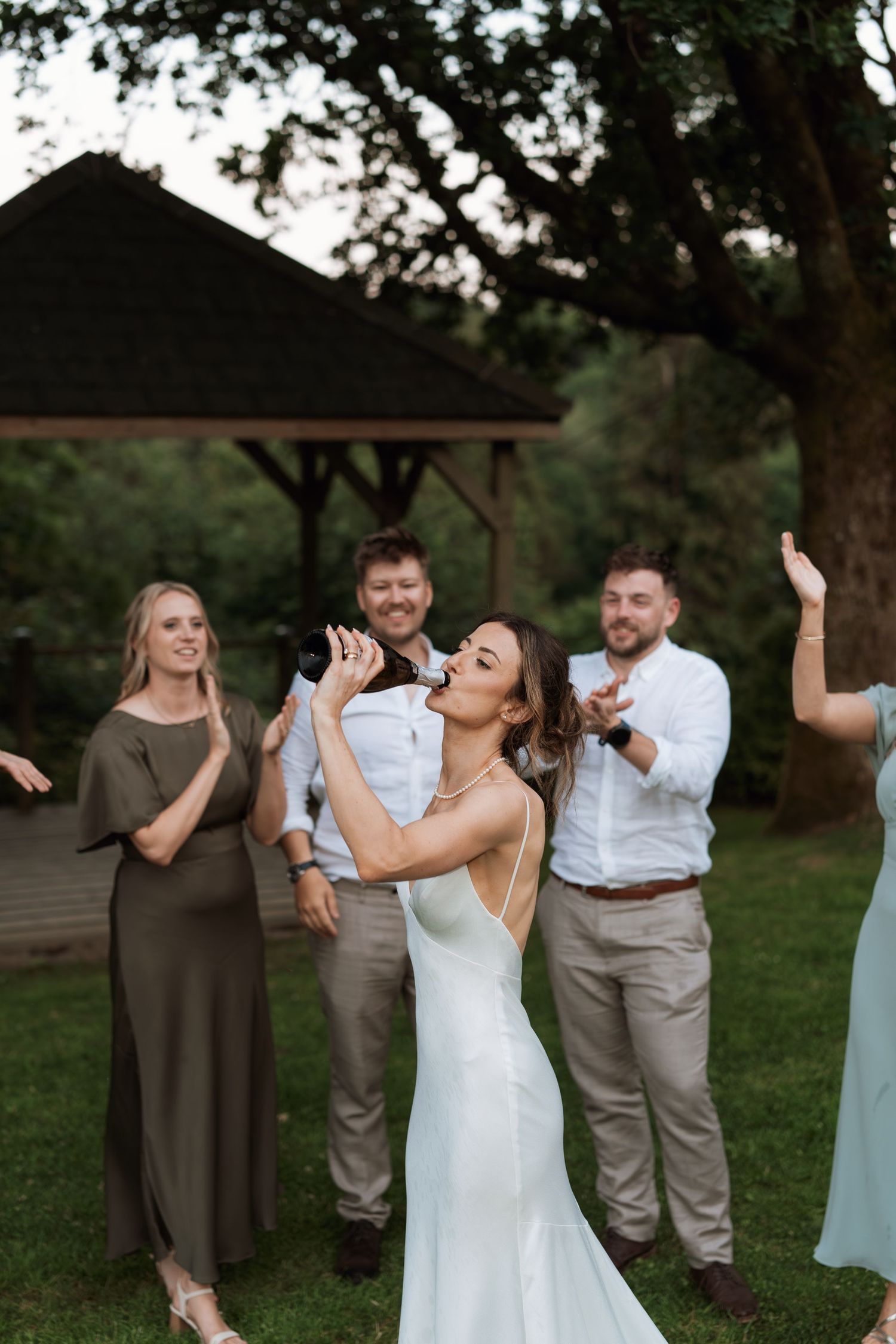 A wedding celebration scene with people joyfully reacting during an outdoor reception.