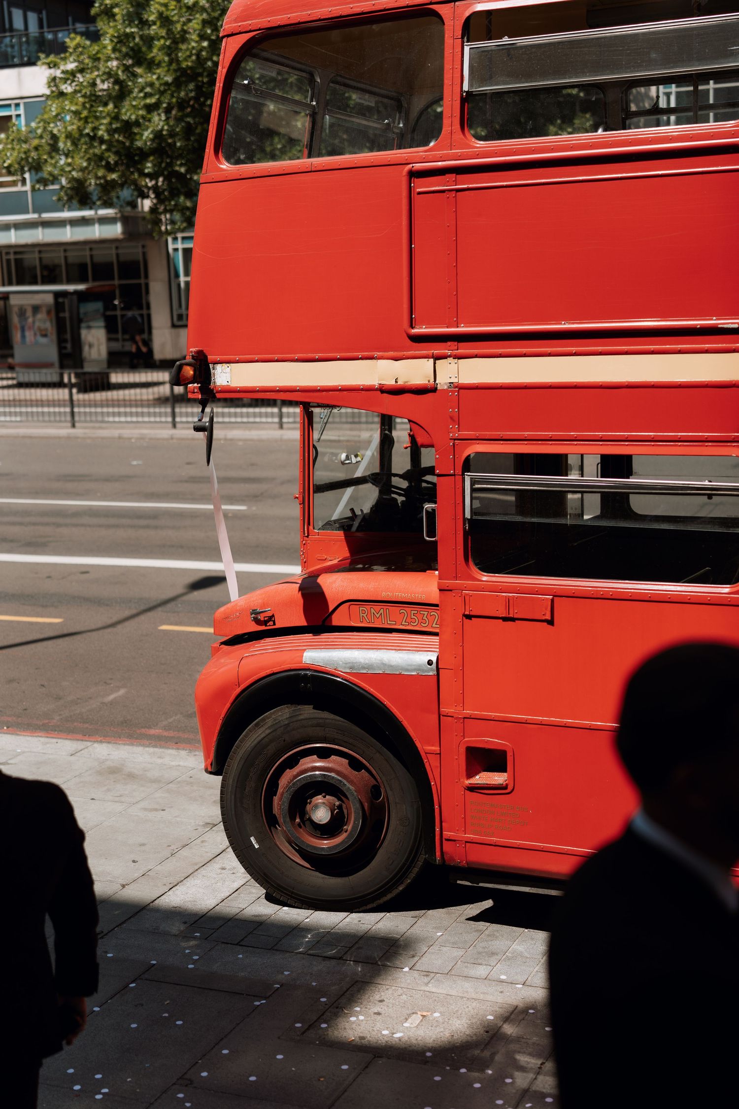 Sequence of red double-decker bus sections photographed in bright sunlight.