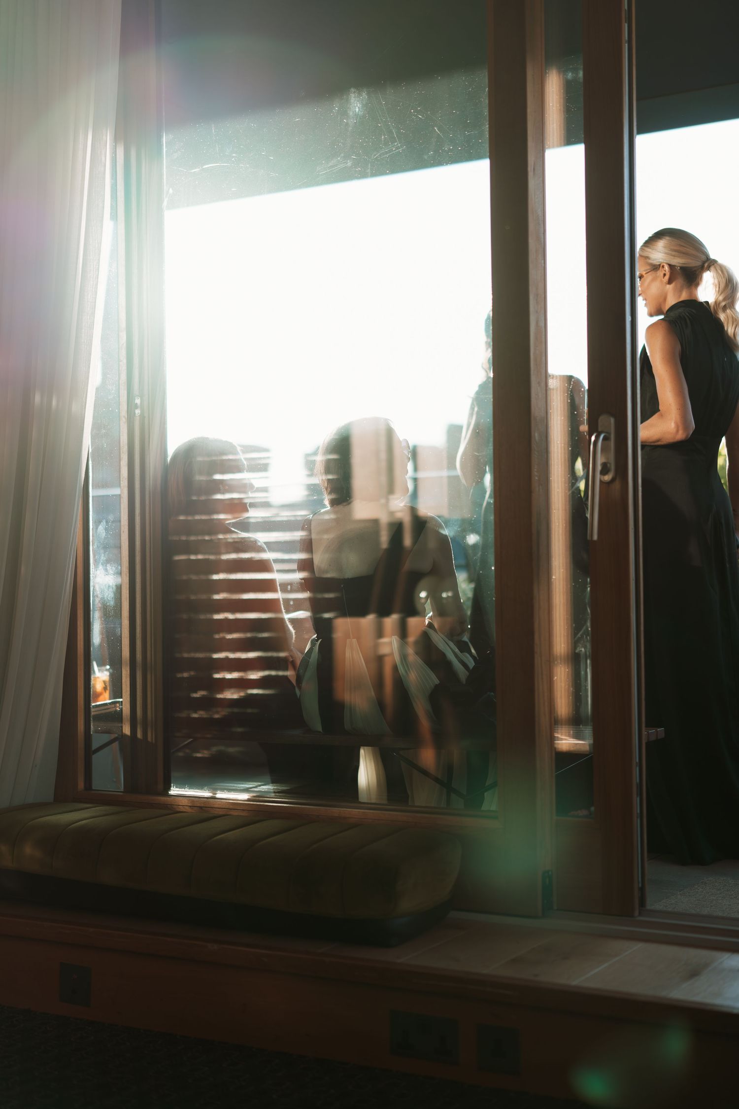 Silhouettes visible through window panes with dramatic lighting and lens flare.