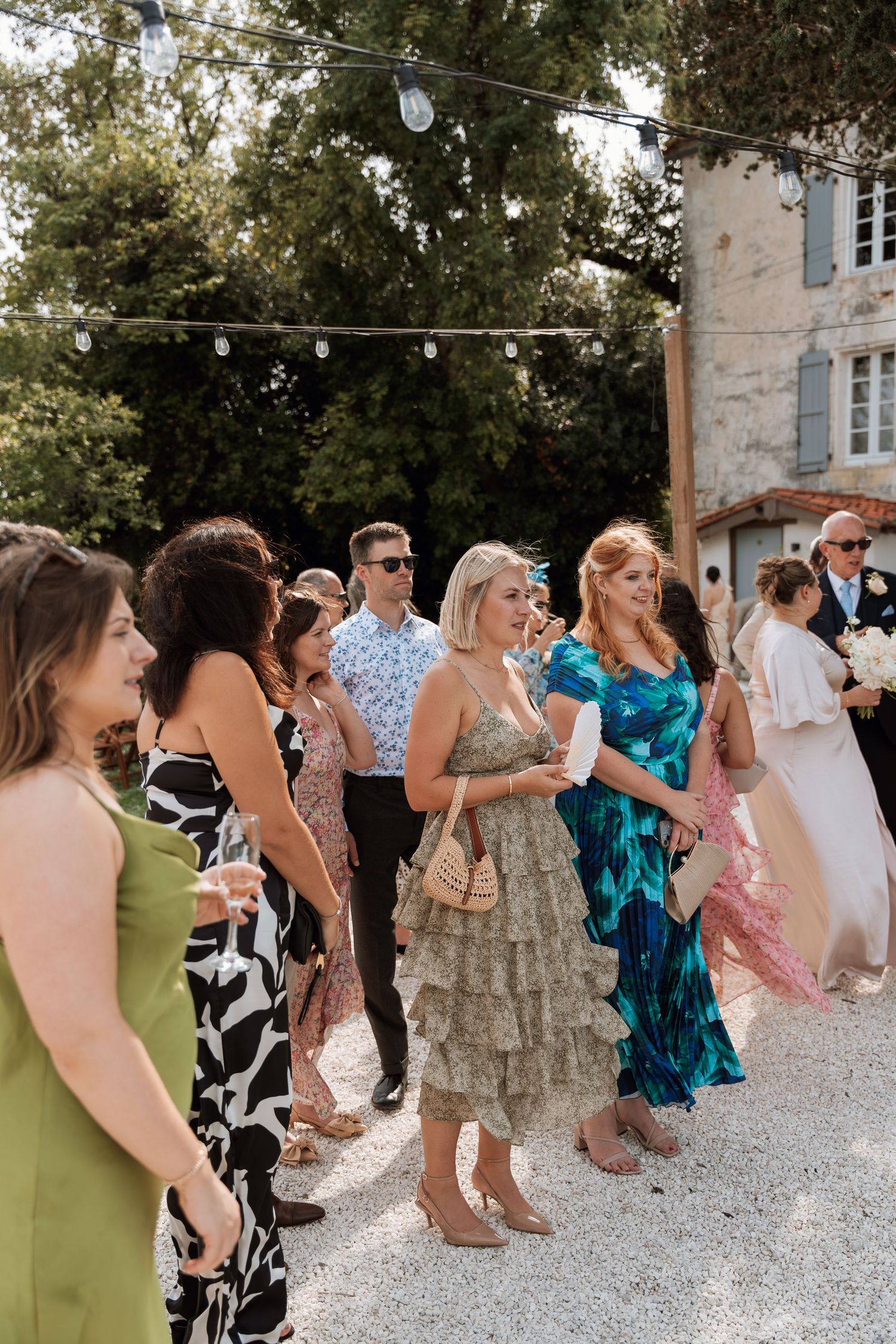 Wedding guests dancing and celebrating on a gravel patio next to a stone building.
