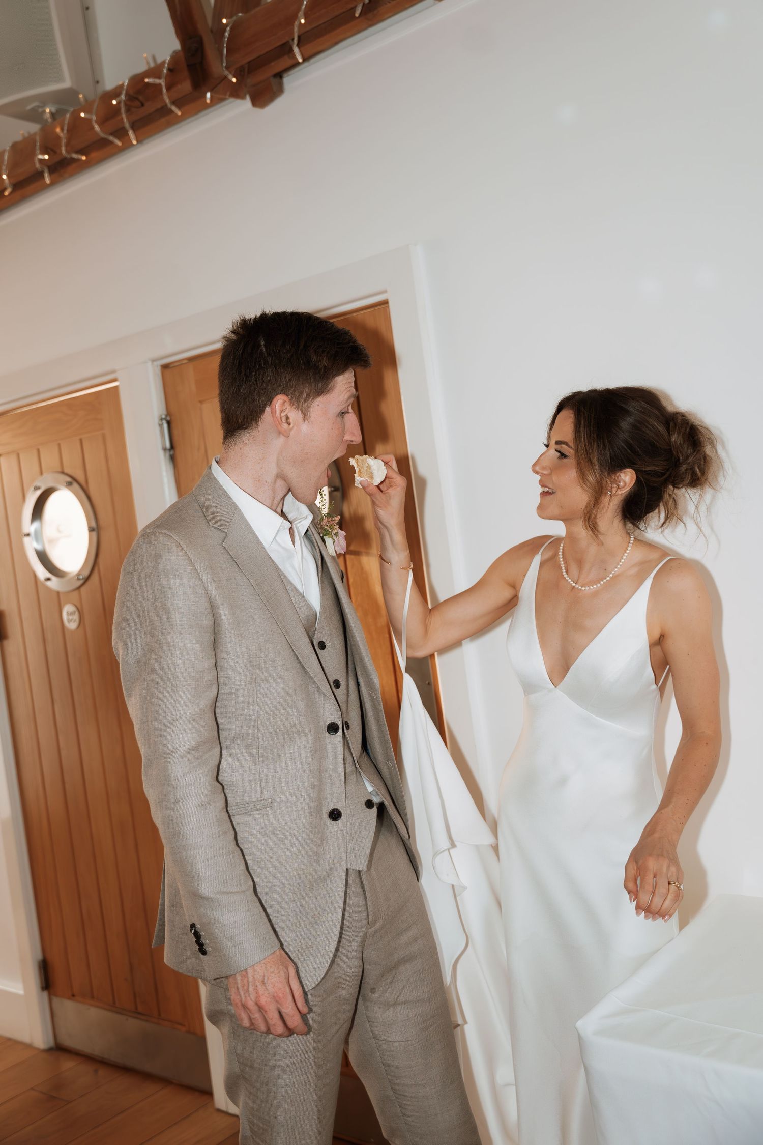Playful dancing moments captured between couple in white dress and light gray suit indoors.