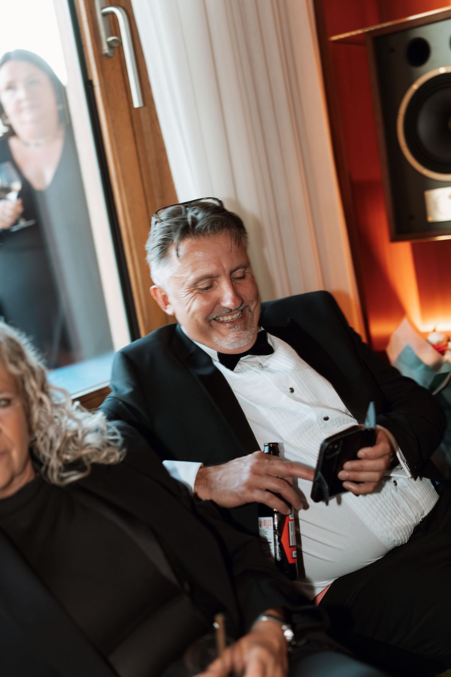 Wedding guests enjoying candid moments at reception in warm lighting.