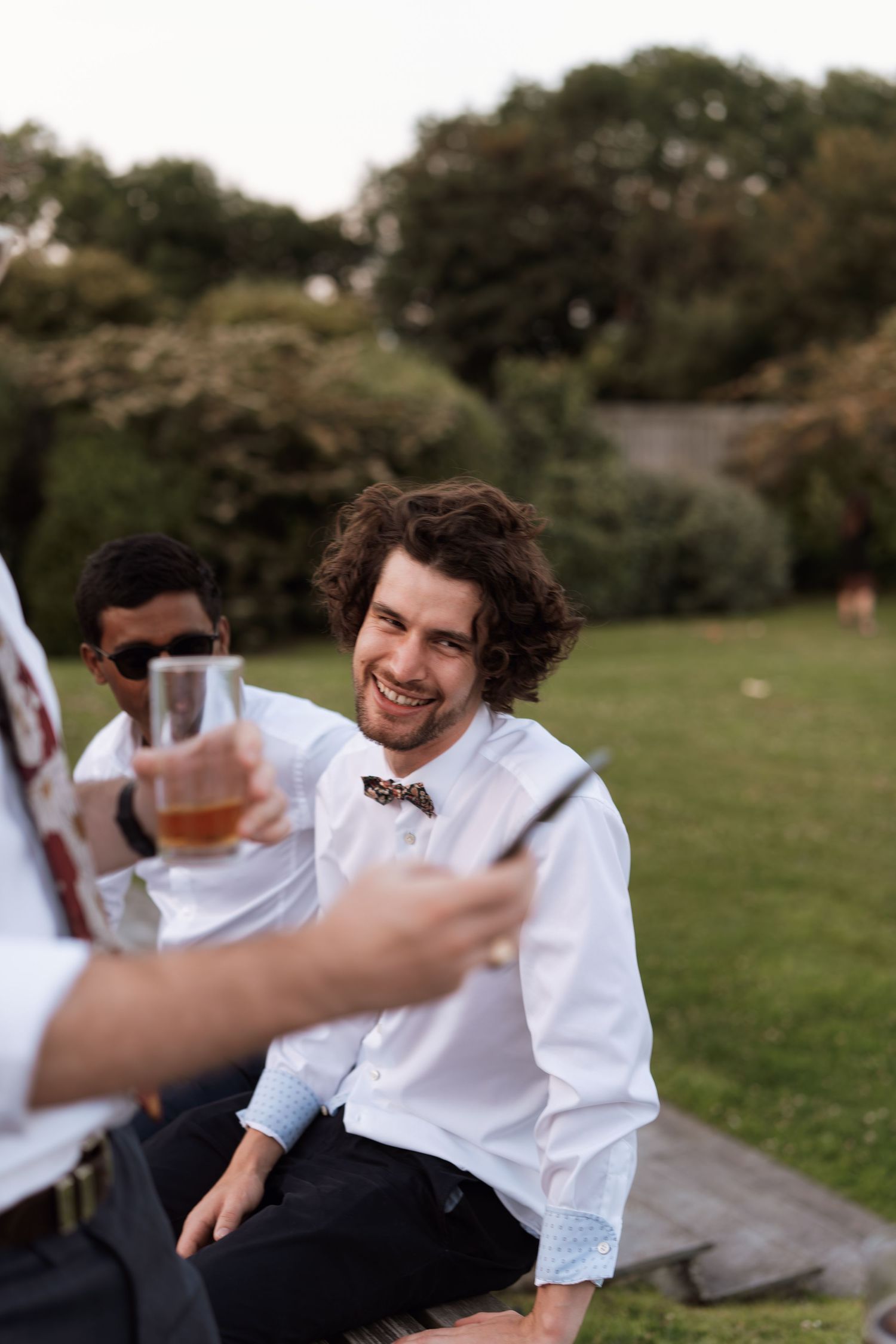 Candid laughter and joy during outdoor wedding celebration on grass.