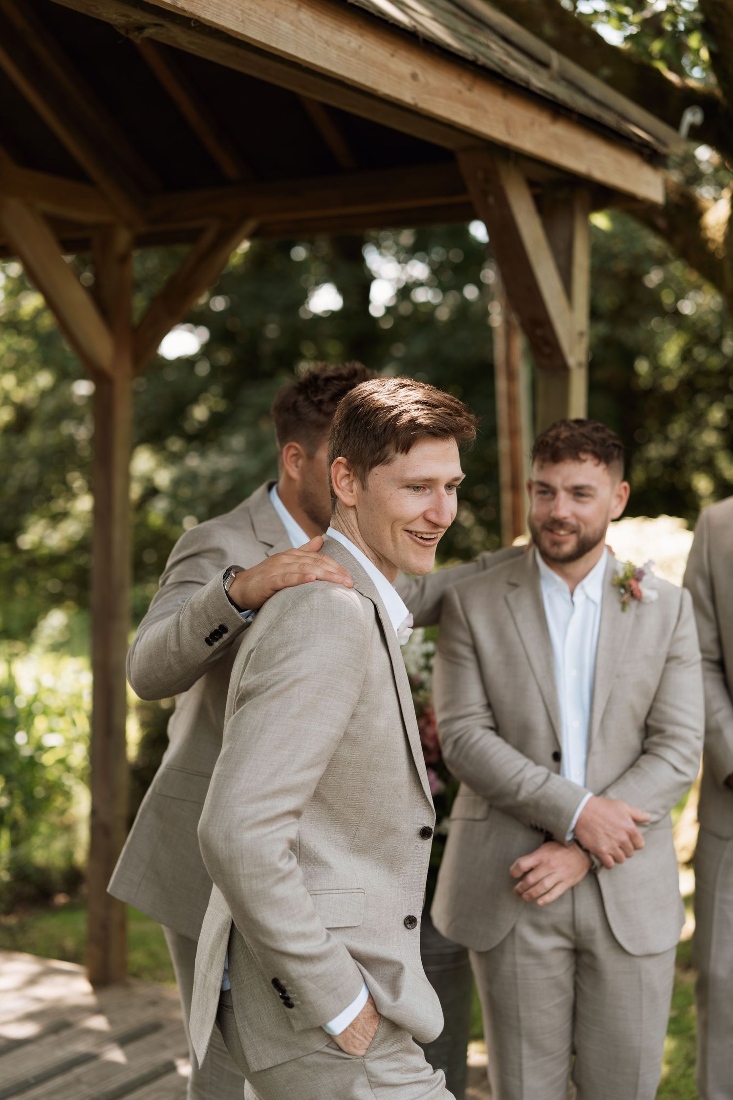 Groomsmen in light gray suits share laughs and jokes during wedding day portraits.