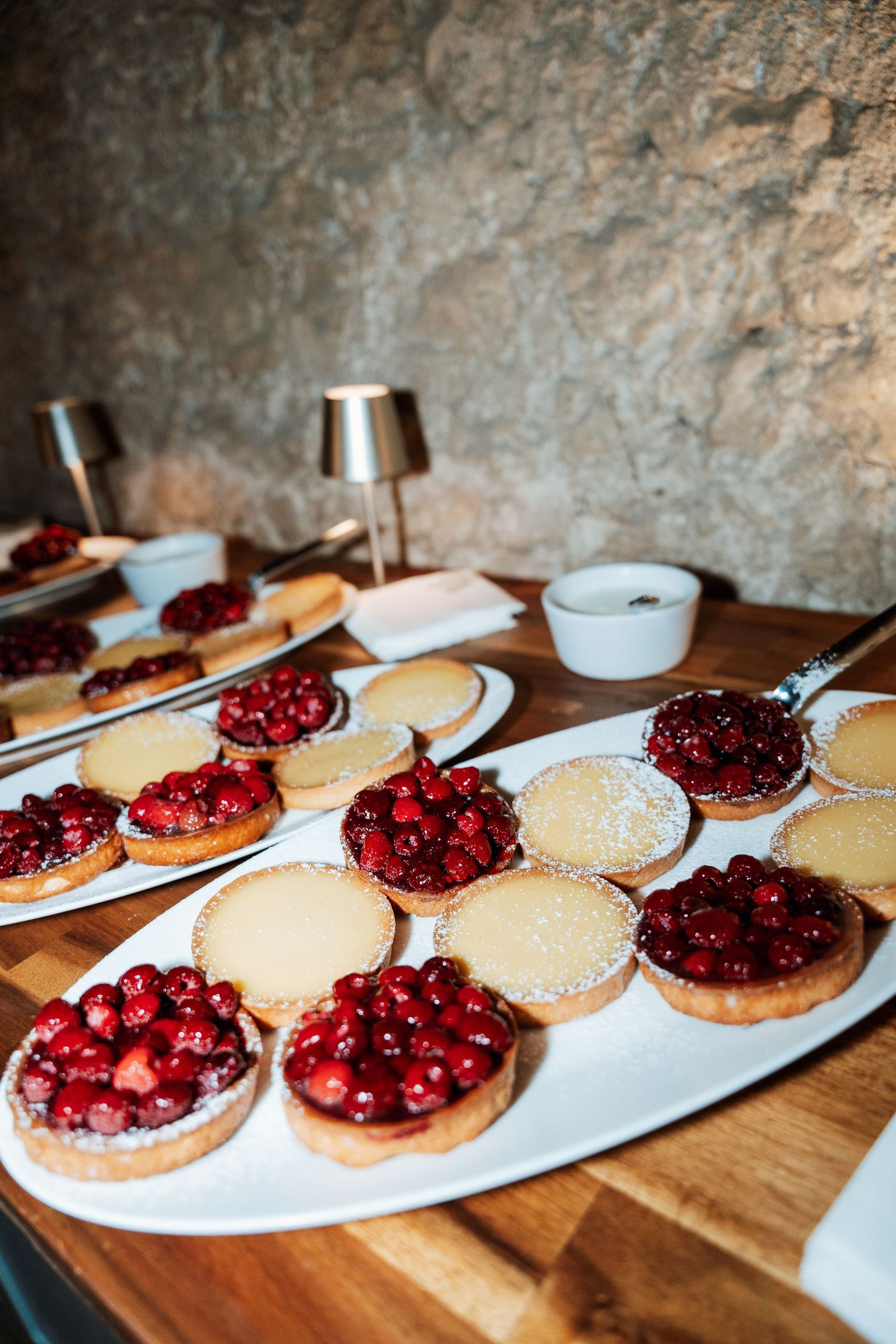 Fresh berry tarts lined up on white plates with powdered sugar dusting.