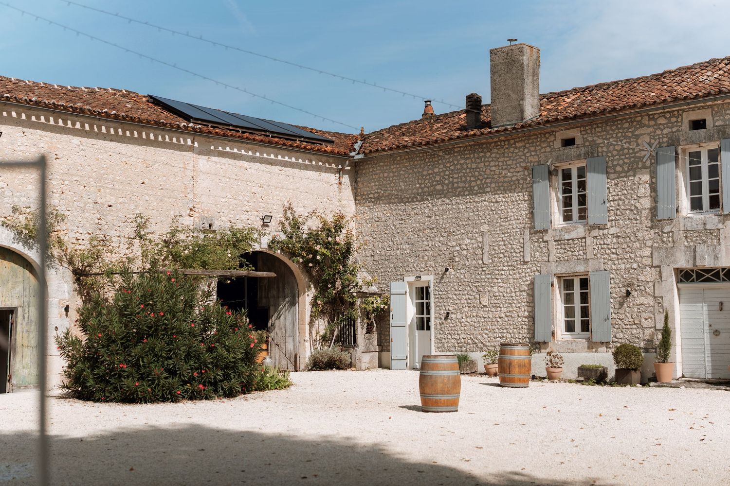 Traditional white stone buildings with terracotta roofs and blue shutters in a Mediterranean style.