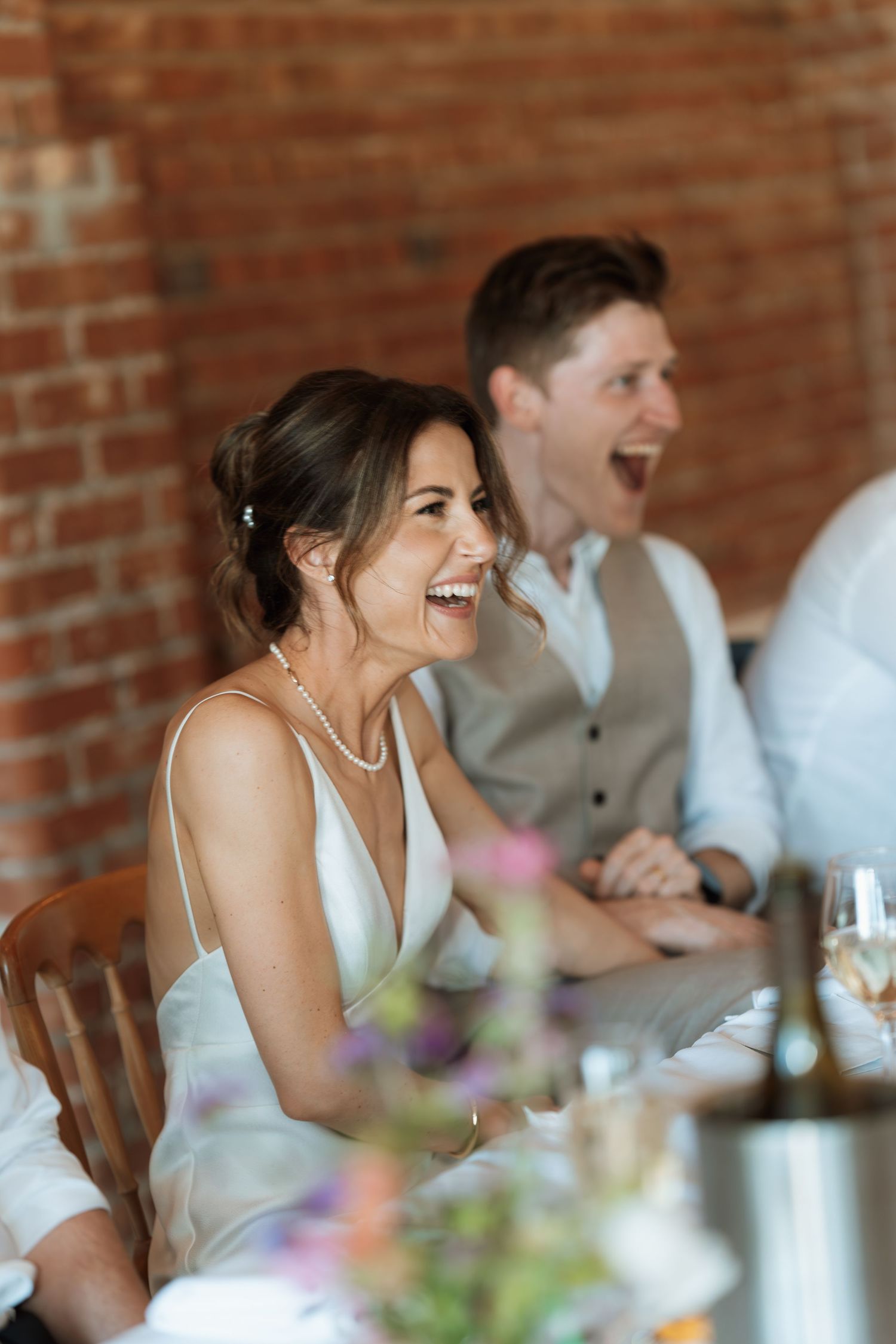 Candid moment of joyful laughter during wedding reception speeches.