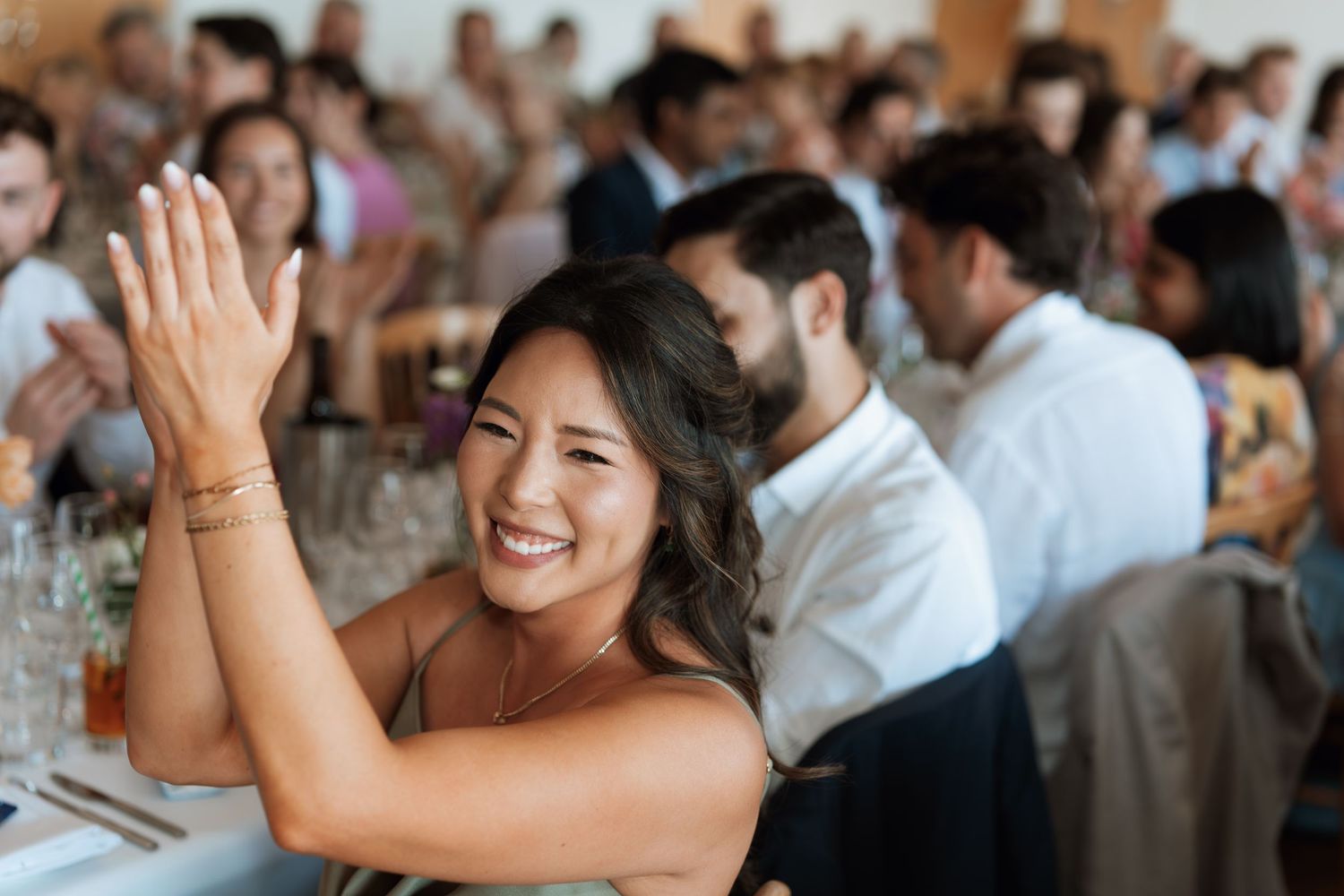Wedding guest clapping and smiling during reception celebration.