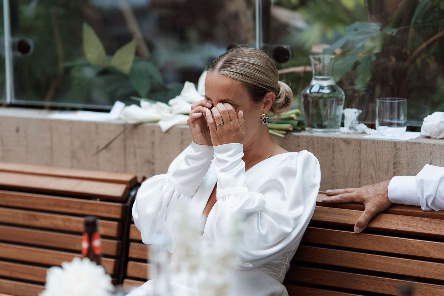 Person in white dress shows emotional reaction during wedding celebration.