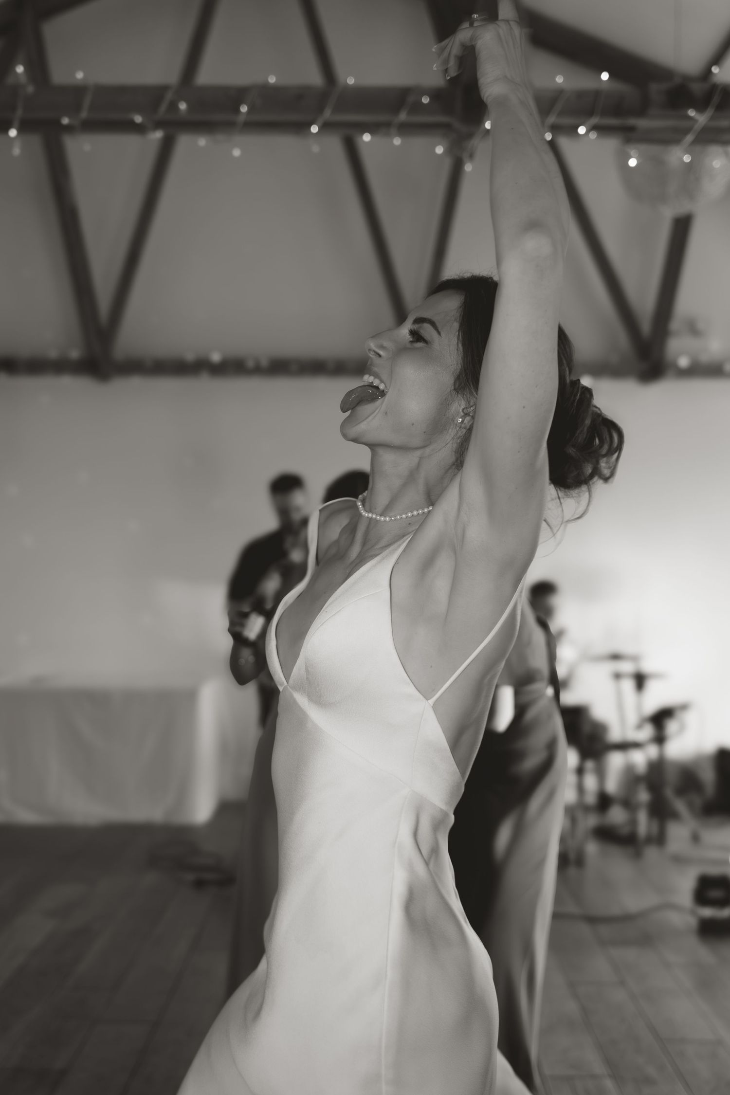 Black and white photo of elegant dance movements in white dress at indoor venue.