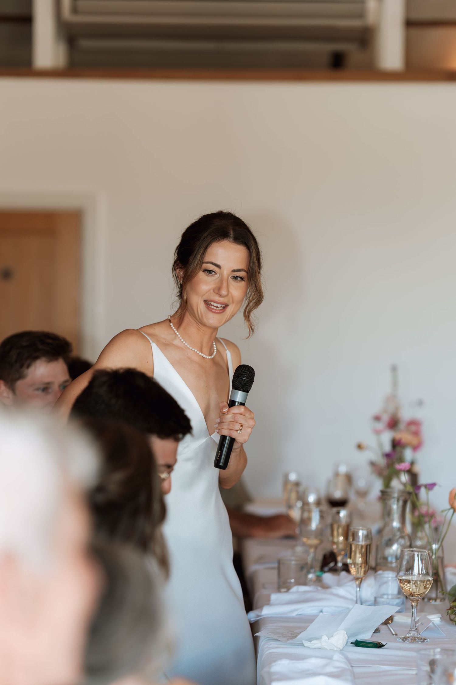 Wedding reception table setting with guests enjoying speeches and laughter.