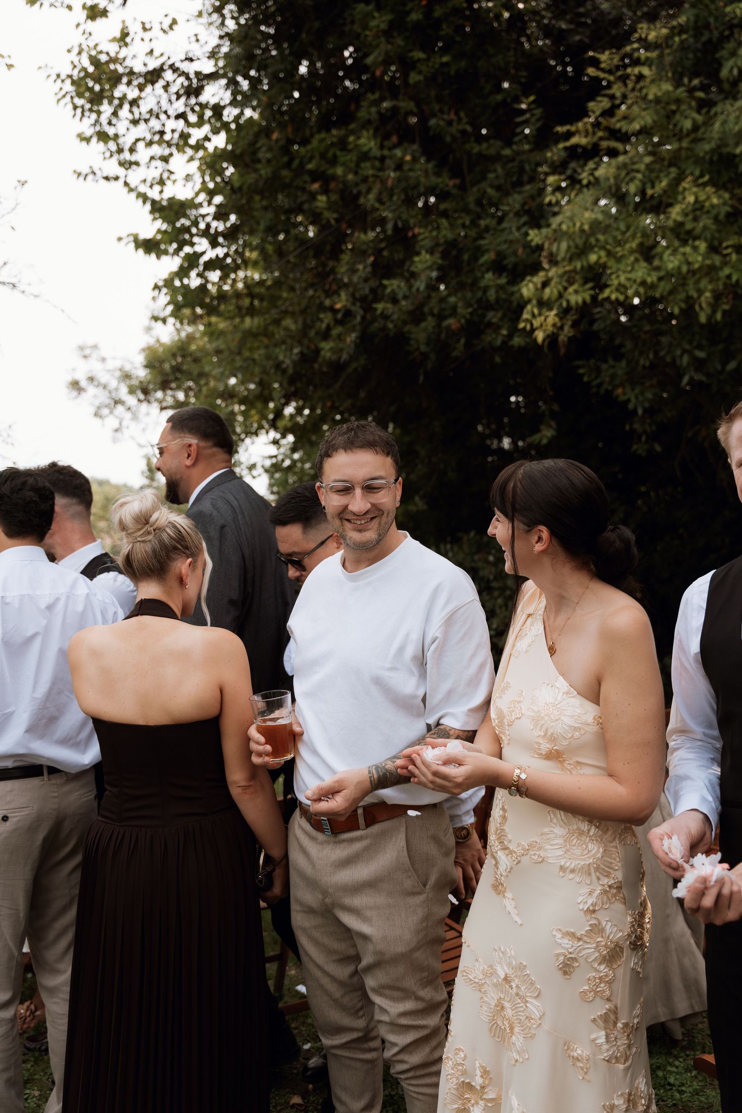 Wedding guests in formal attire socialize during outdoor cocktail reception.