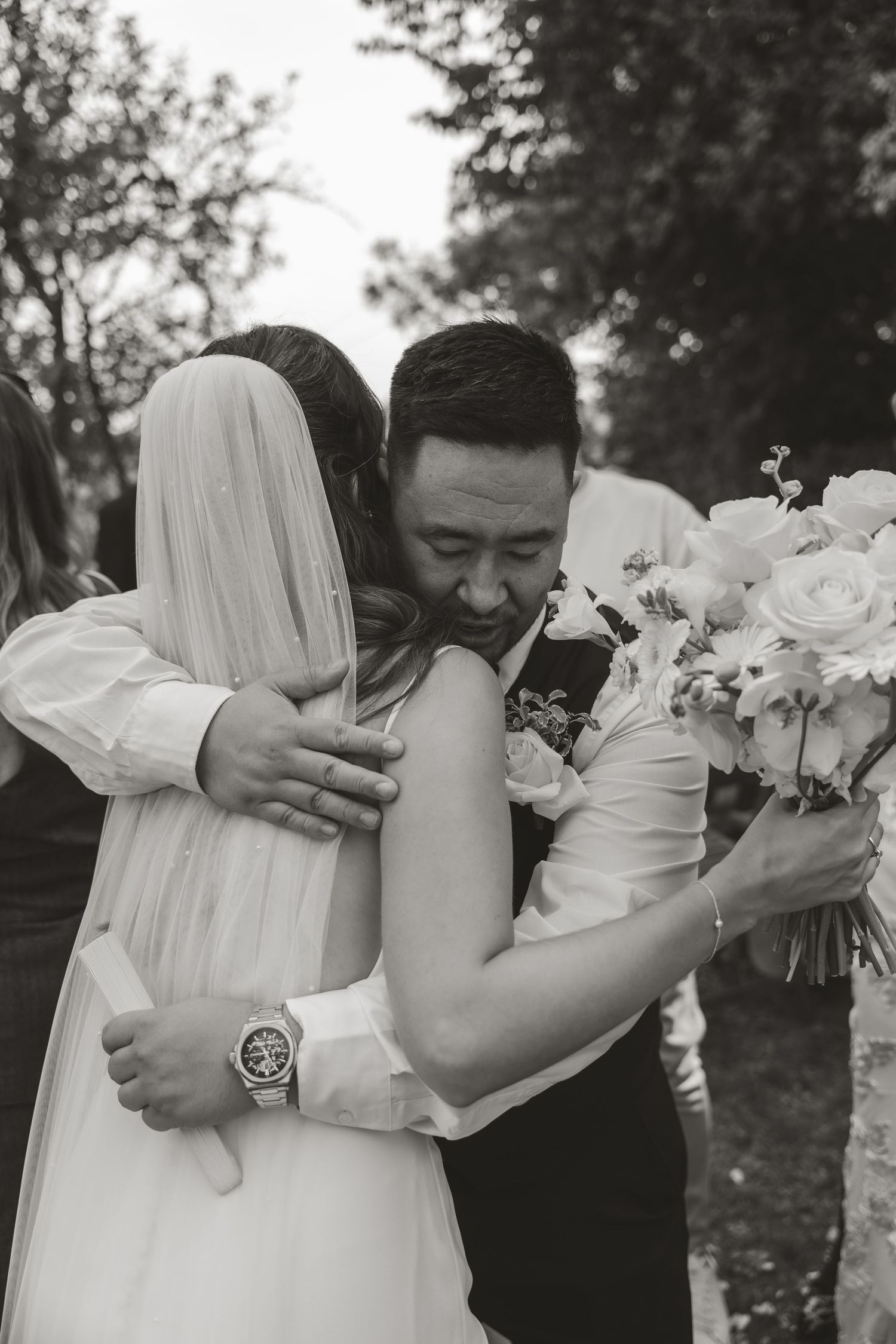 A tender embrace between newlyweds during an outdoor wedding ceremony with white roses.