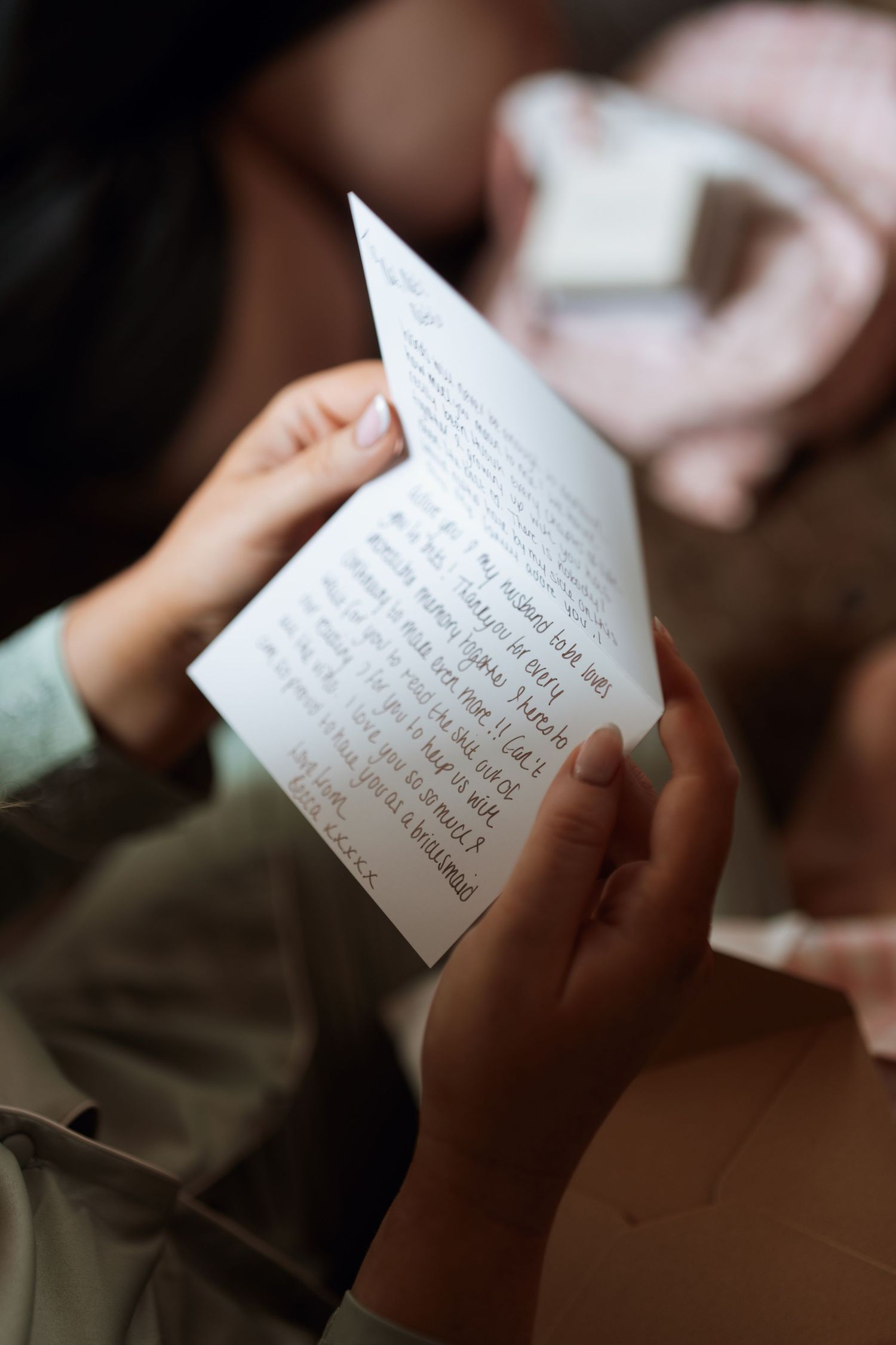 A person's hands hold a handwritten note or letter in soft natural lighting.