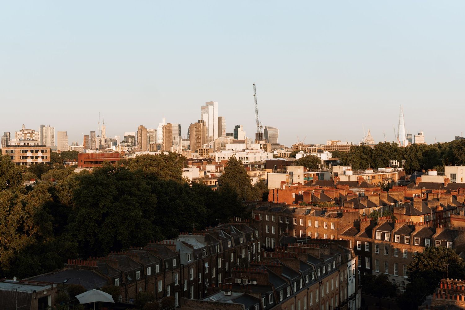 Aerial view of London cityscape showing urban rooftops and skyscrapers during sunset.