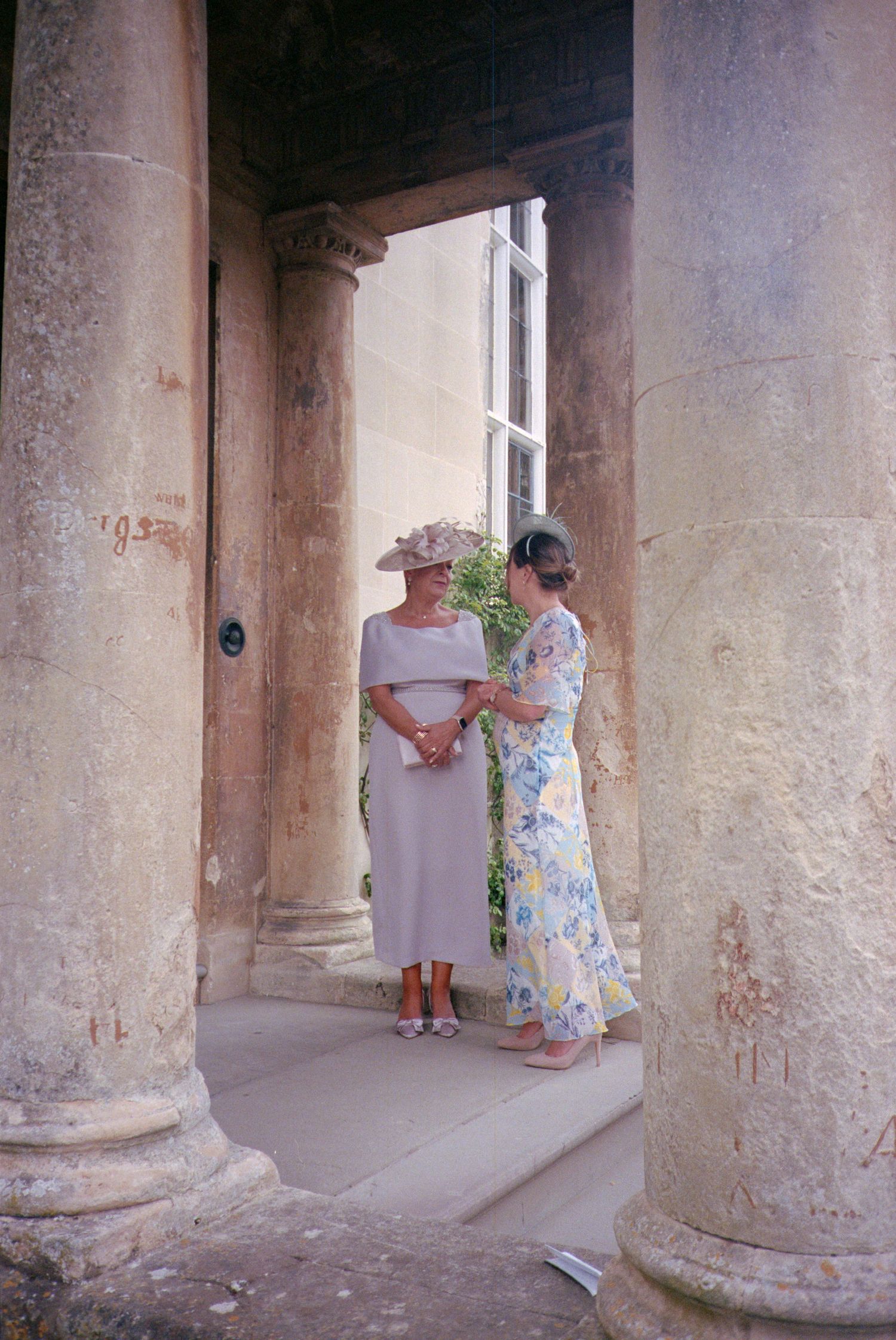 Stone columns and archways line a weathered corridor in an ancient building with peeling walls and worn surfaces.
