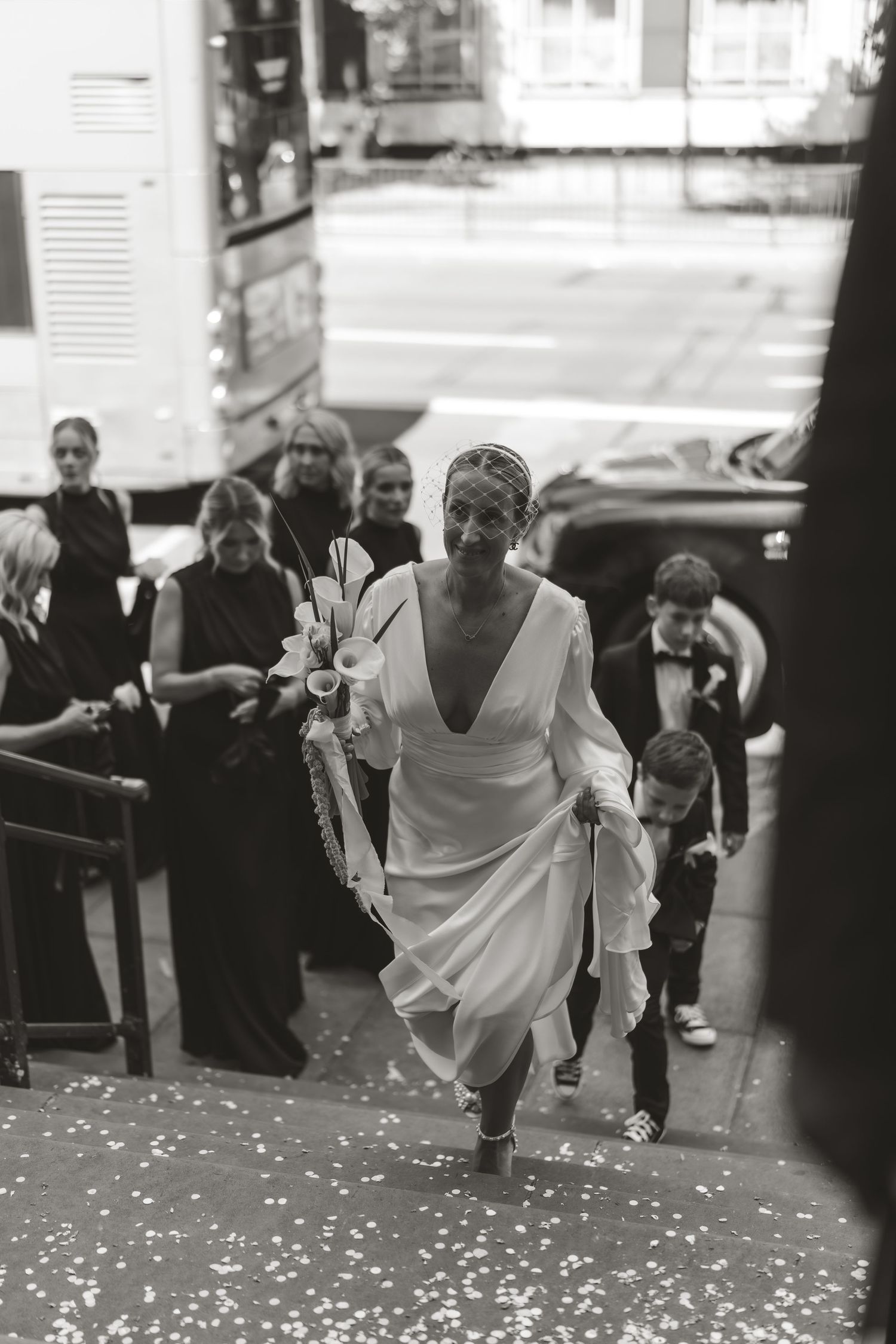 Wedding party runs down a hallway while confetti falls around them in black and white.