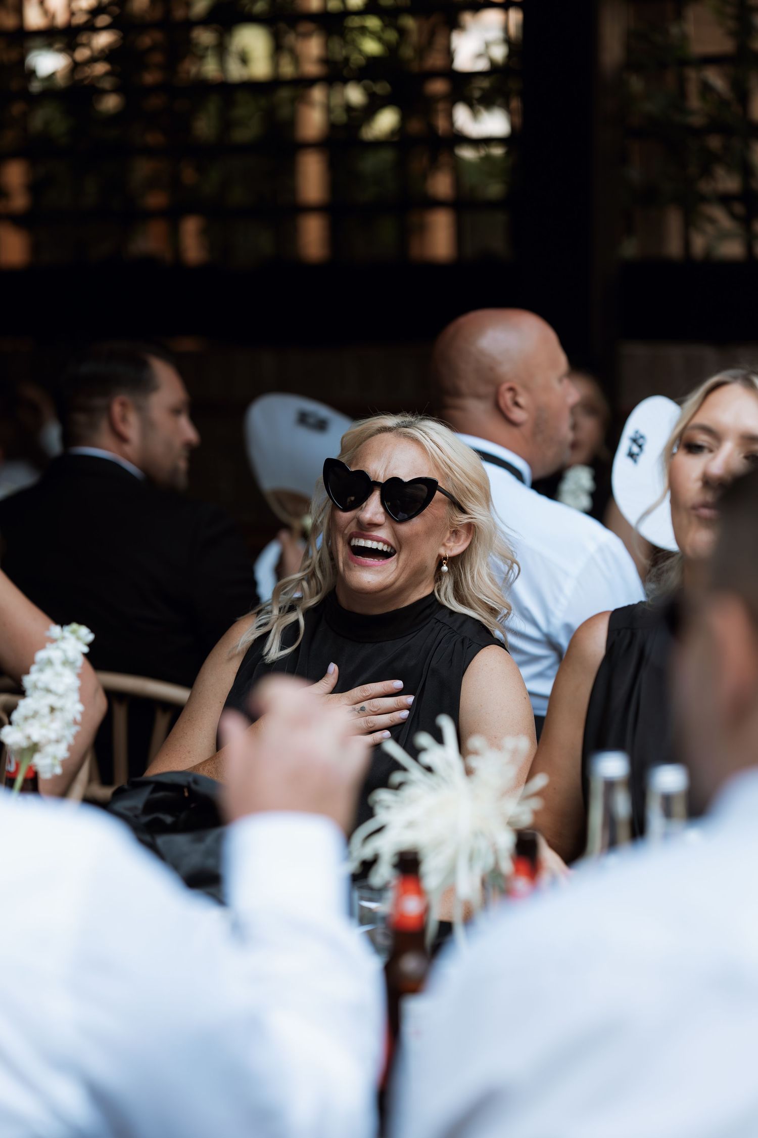 Wedding guests share joyful laughter during an outdoor celebration.