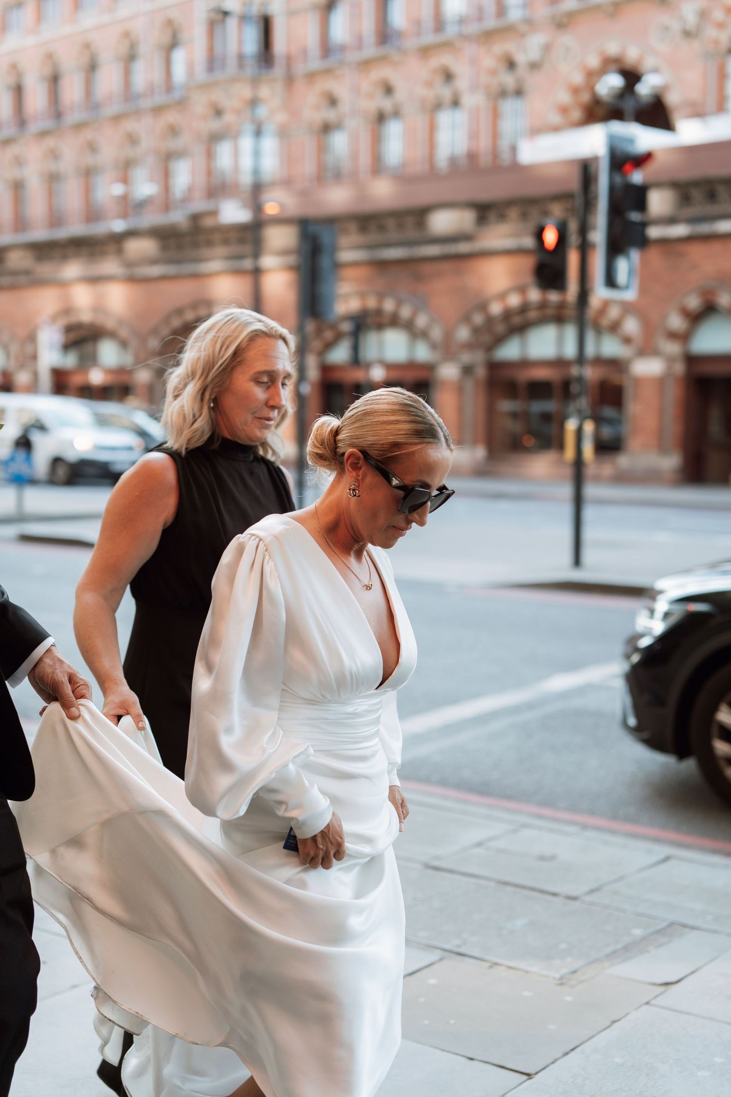 Wedding party members in white and black attire walking along an ornate city street.