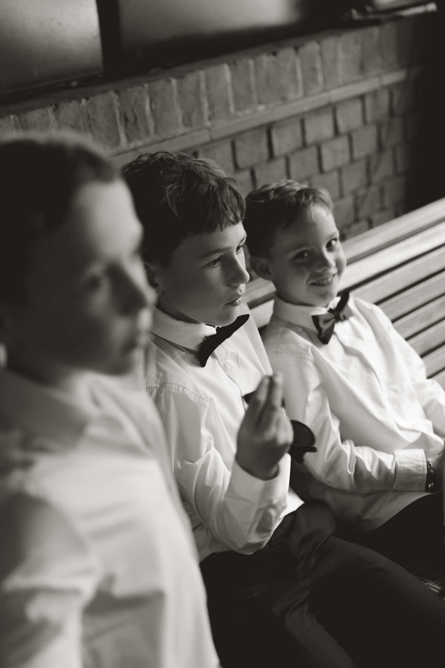 Three people in white shirts seated together in a black and white artistic portrait sequence.
