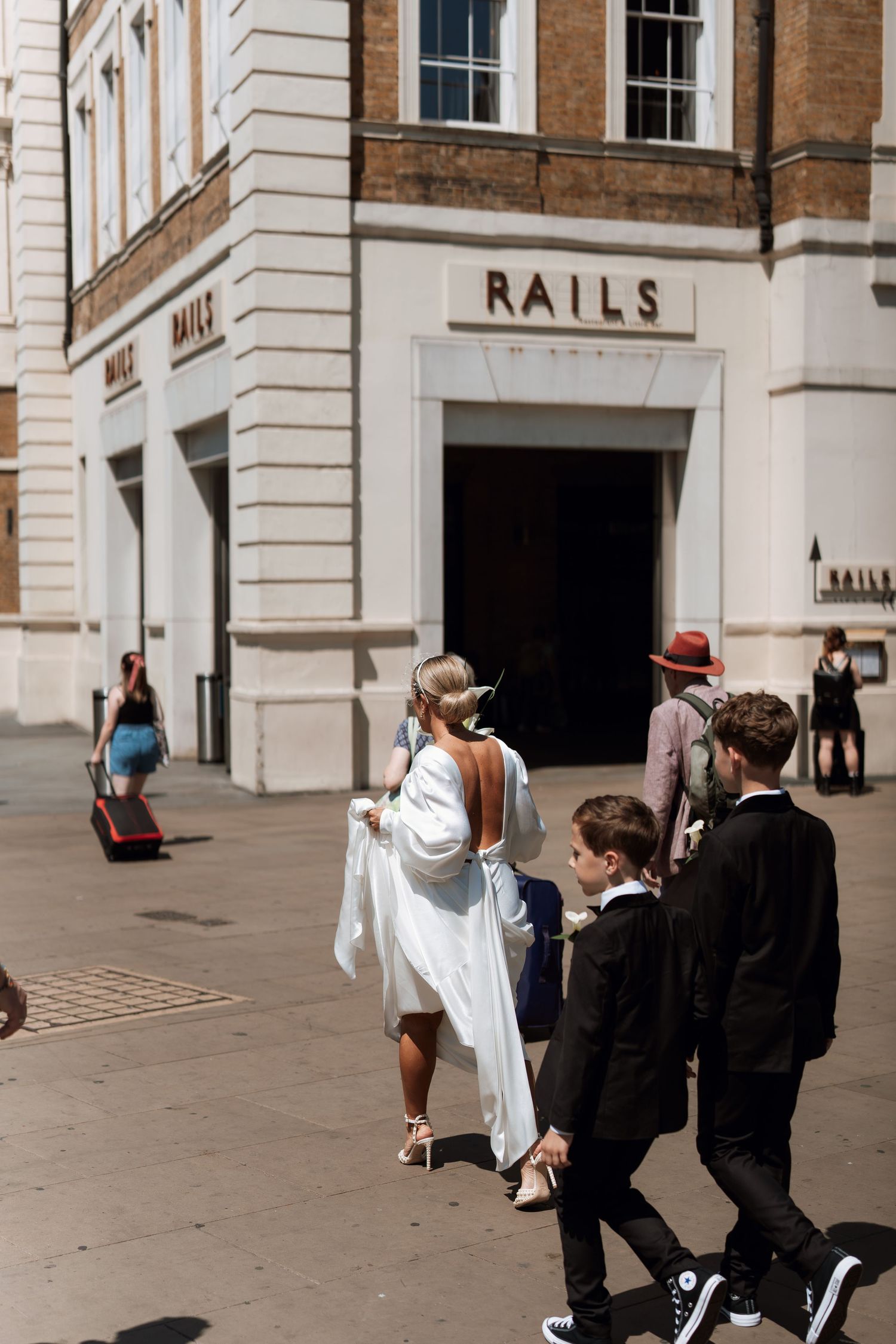 Wedding party walking down a brick-lined urban street with historic architecture.
