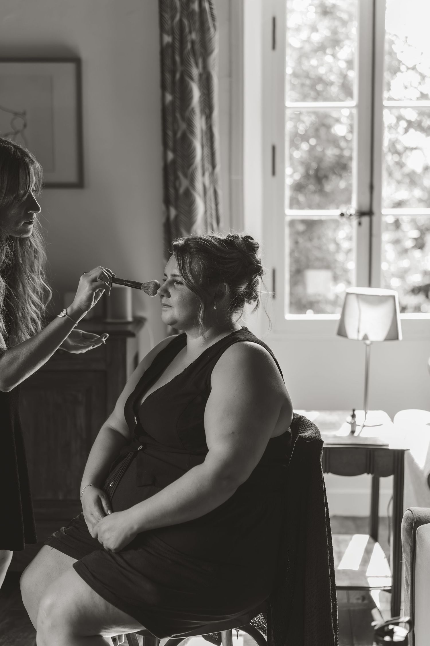 Black and white photo of wedding preparations in a sunlit room.