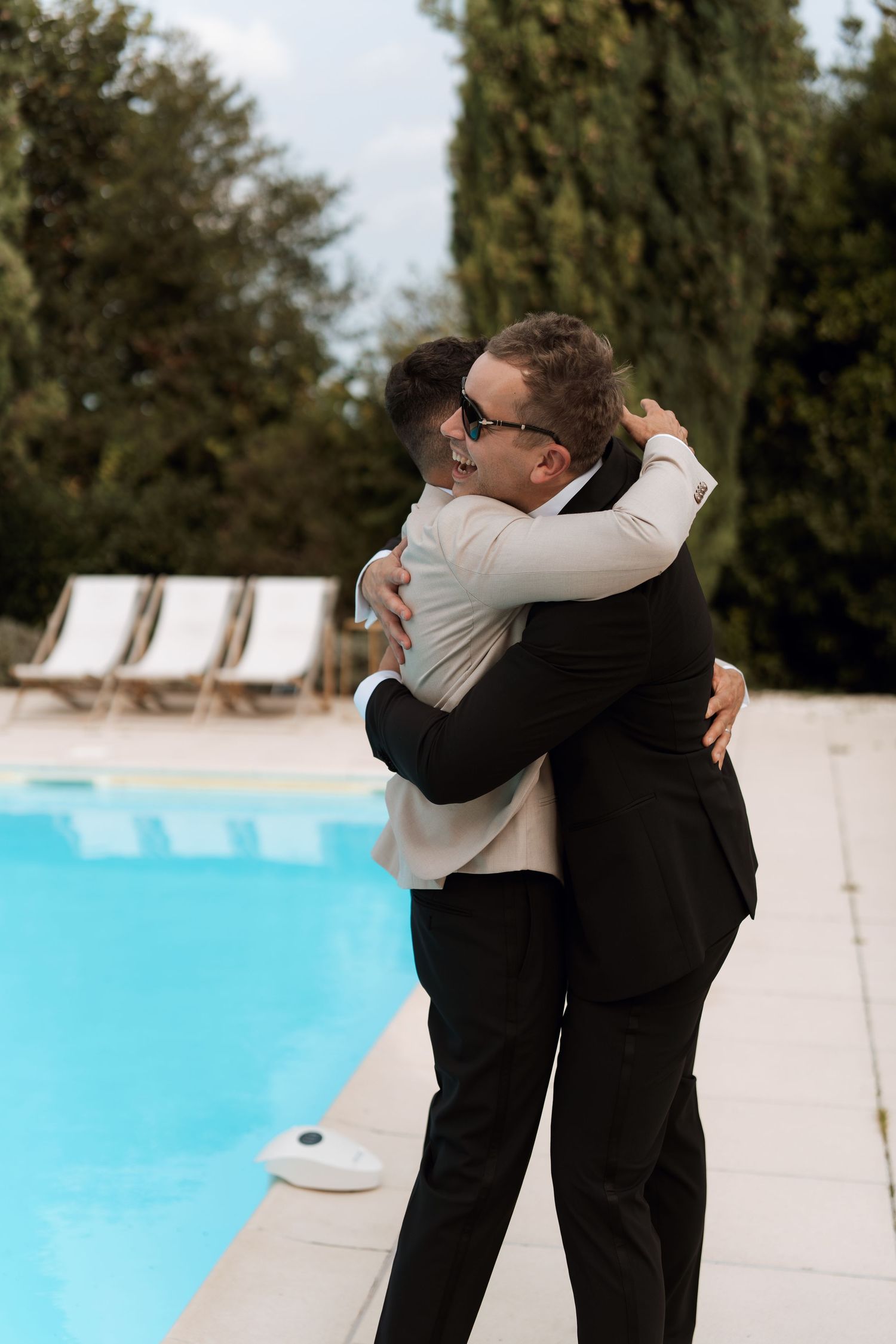 Two people embracing by a swimming pool during a wedding celebration.