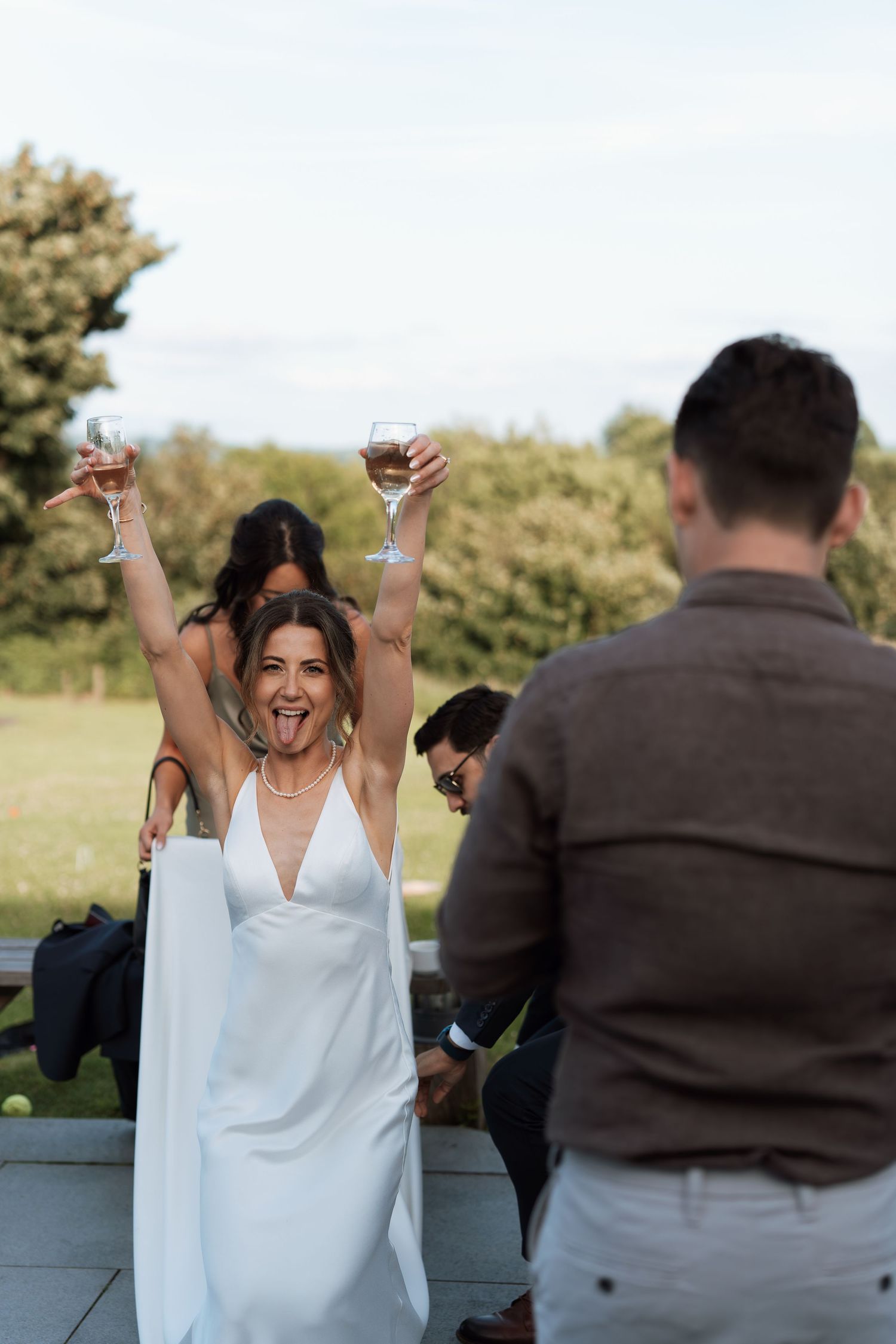 Celebratory scene at outdoor wedding with white dress and joyful expressions.