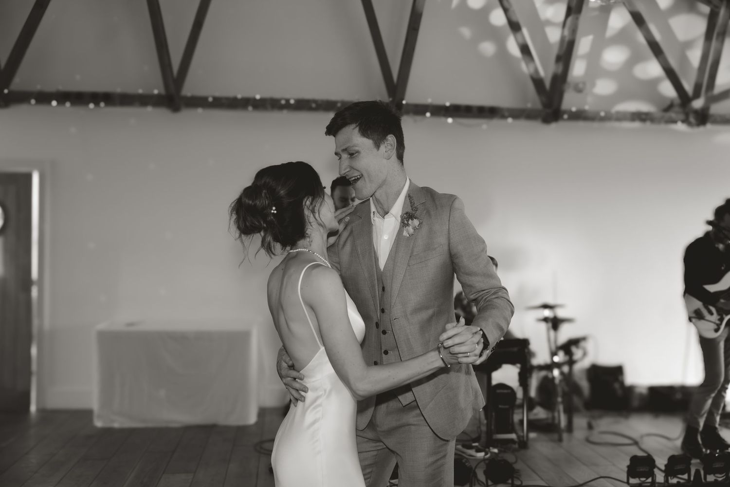 A black and white photo of a couple sharing their first dance at their wedding reception.