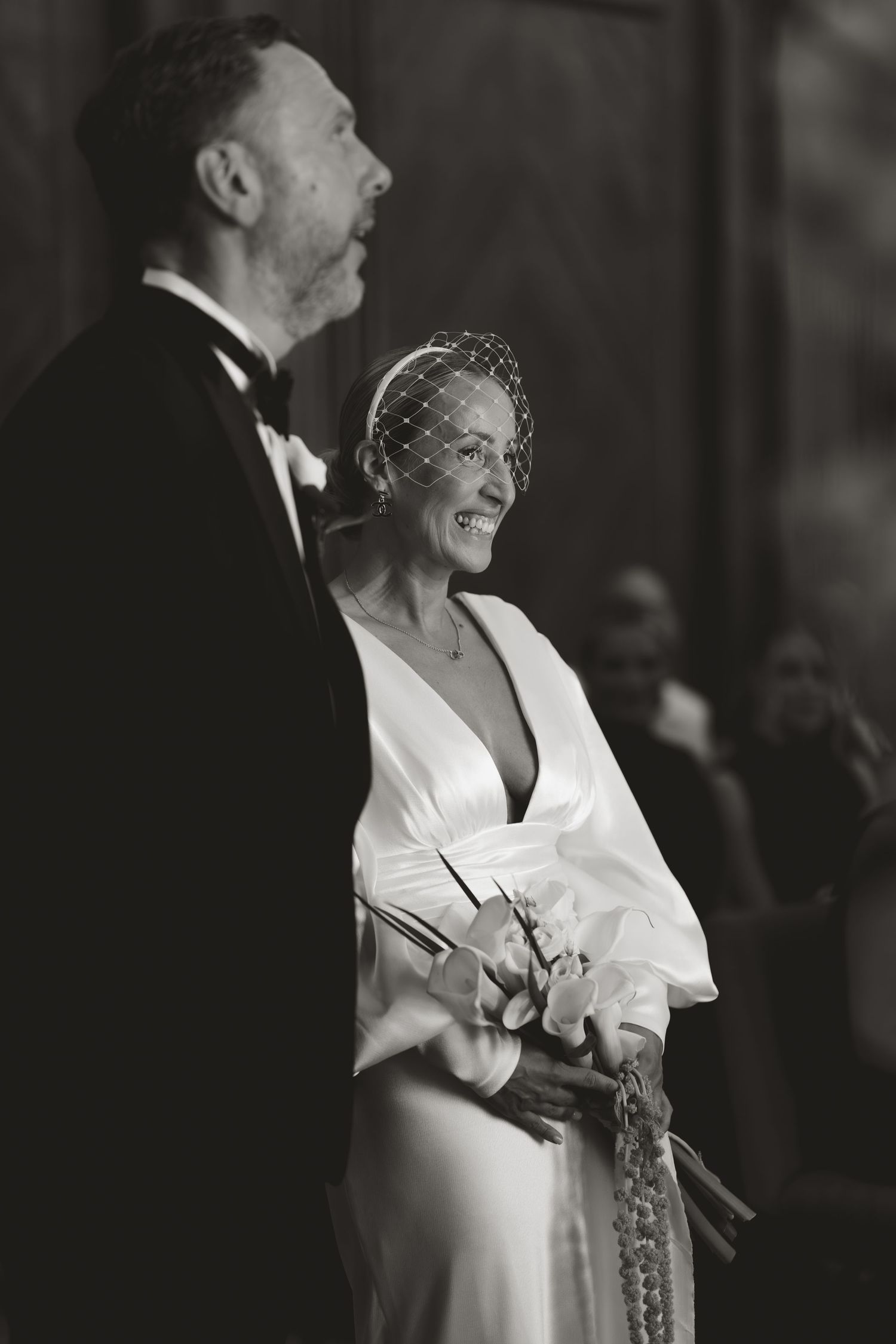 A bride in a white dress laughs joyfully during a wedding celebration.