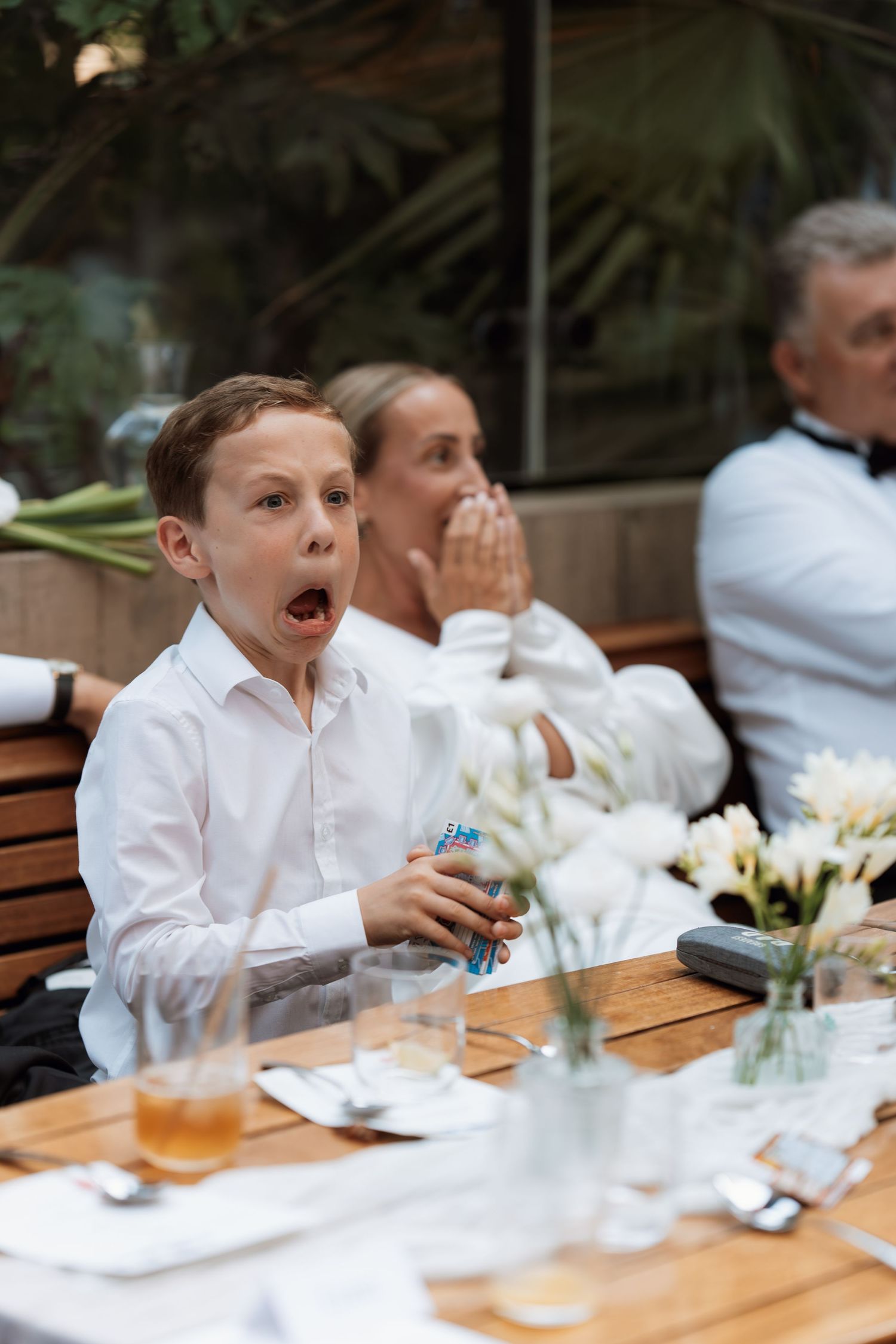 Children in white shirts sitting at a dining table during a formal event.
