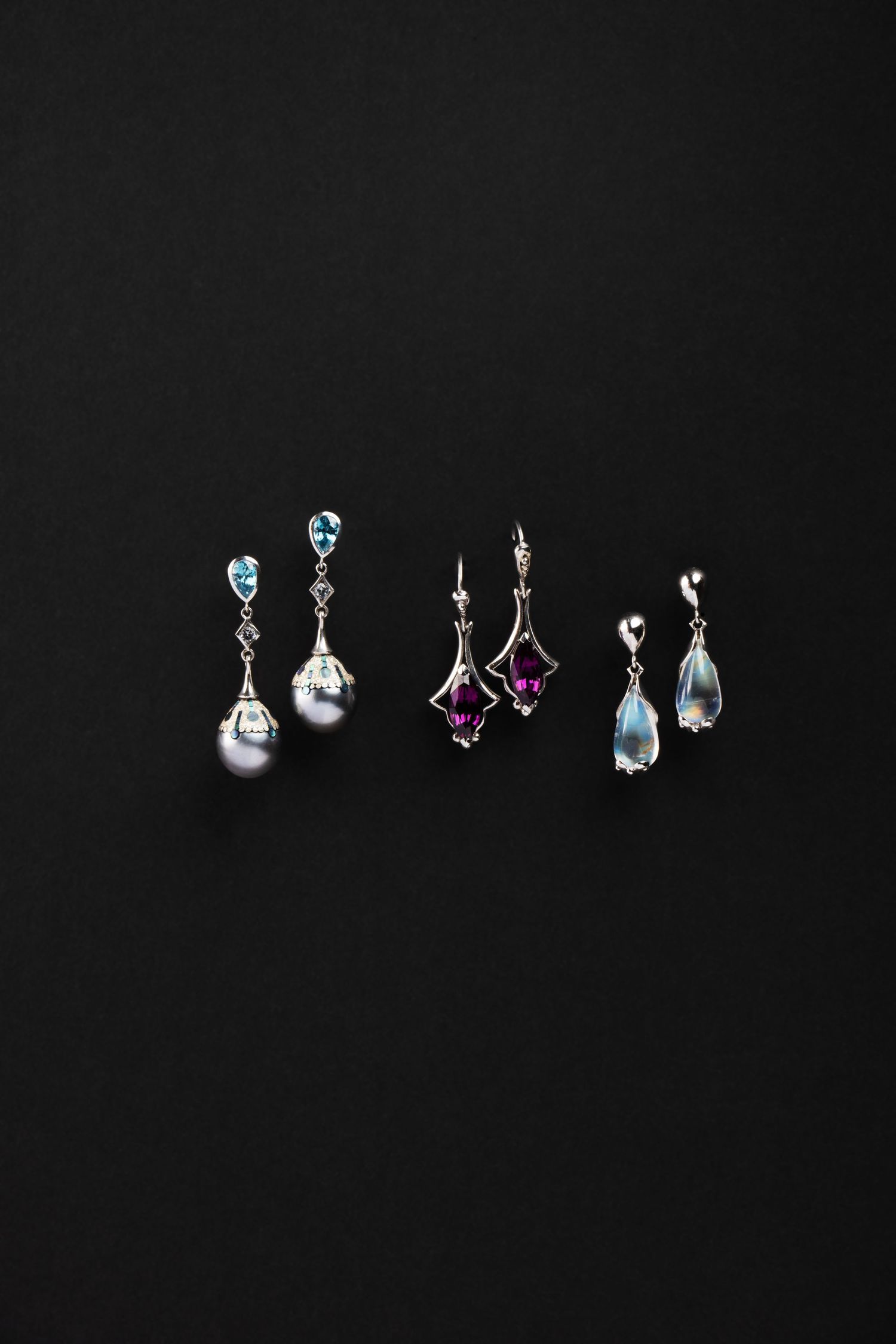 Fine gemstone earrings photographed on black background with dramatic lighting and high contrast detail.