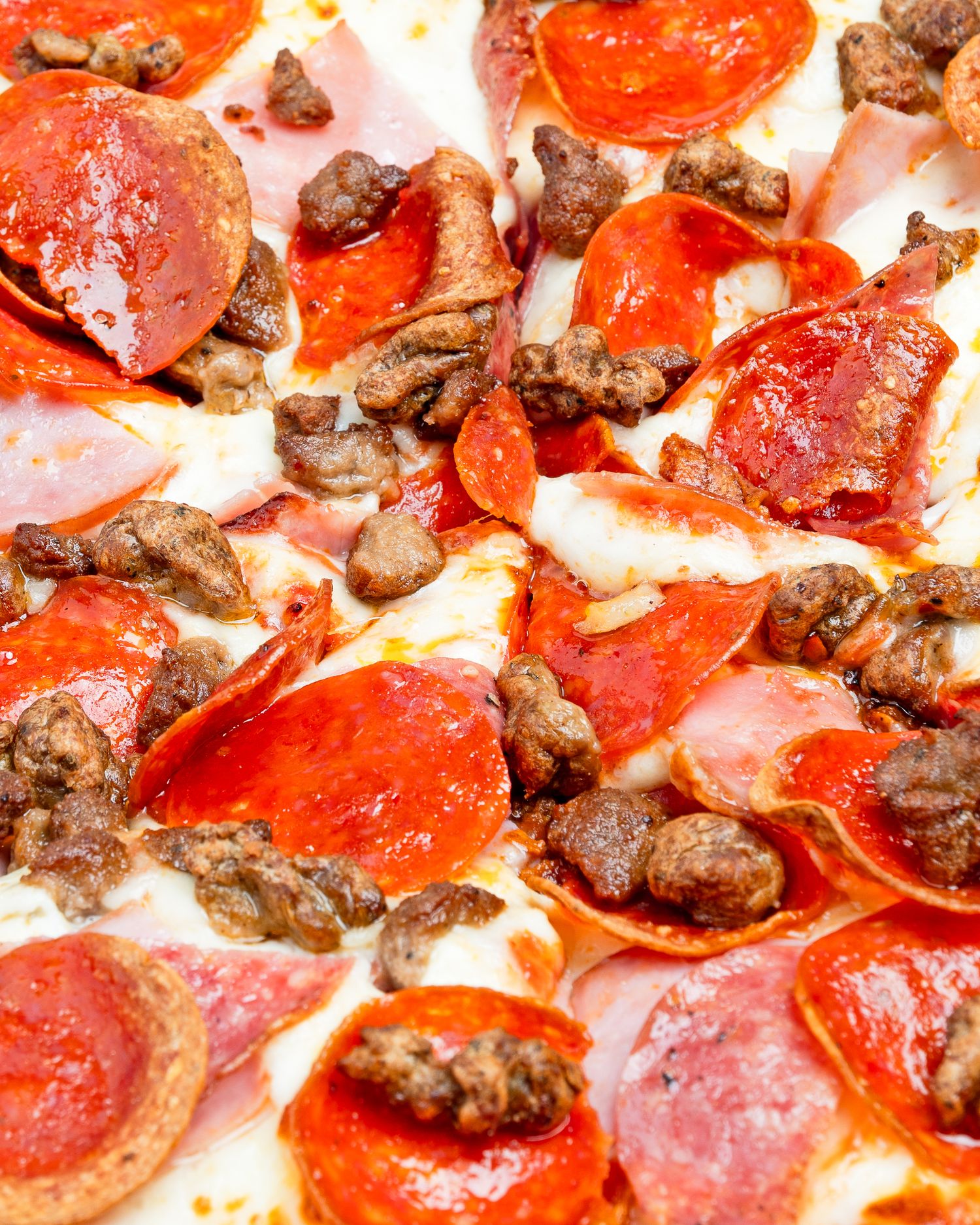 Macro shot of pepperoni and sausage pizza with bubbling mozzarella and rich tomato sauce texture.